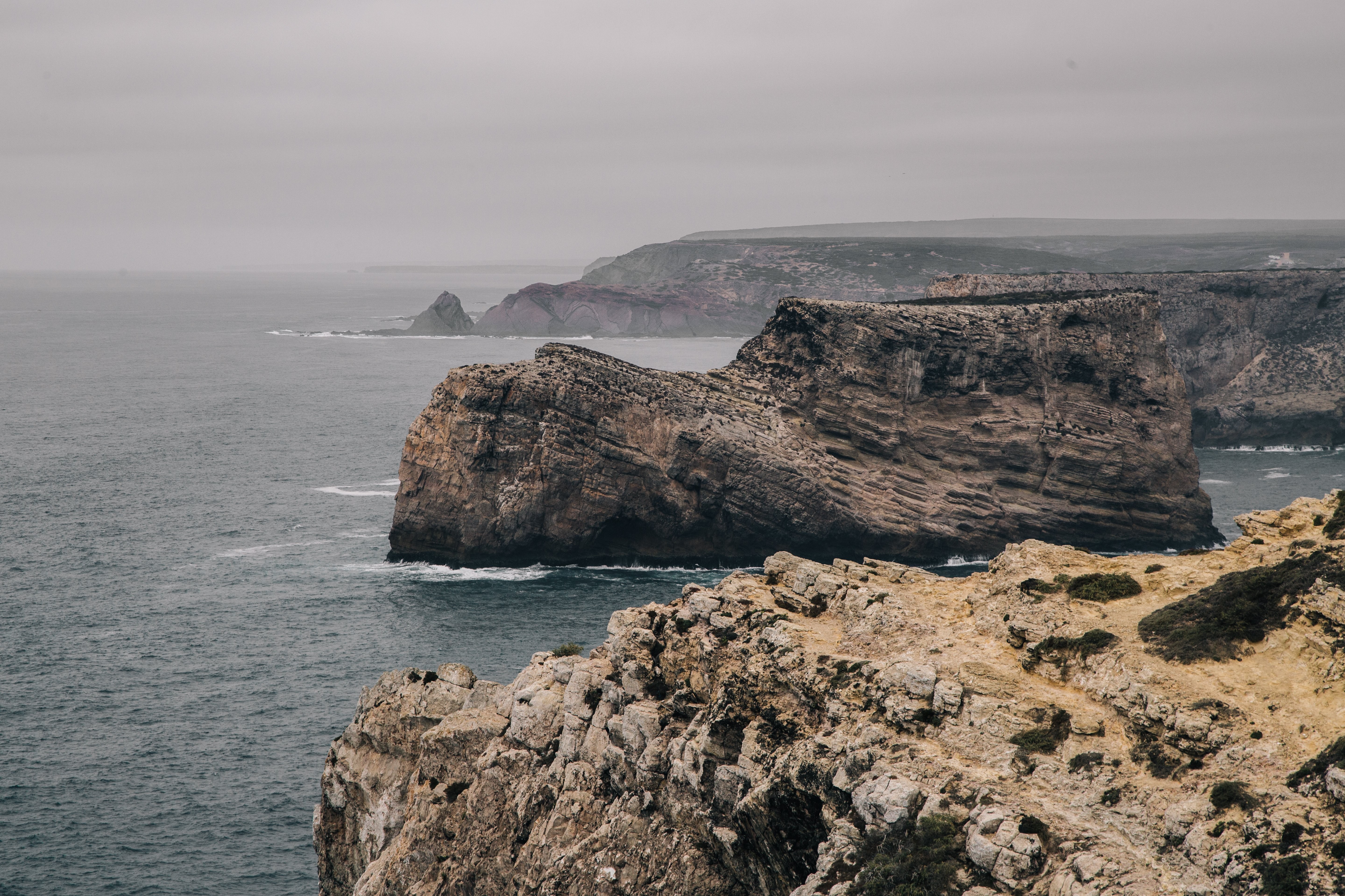 大きな石の露頭が灰色の海の断崖から離れて立っている写真 