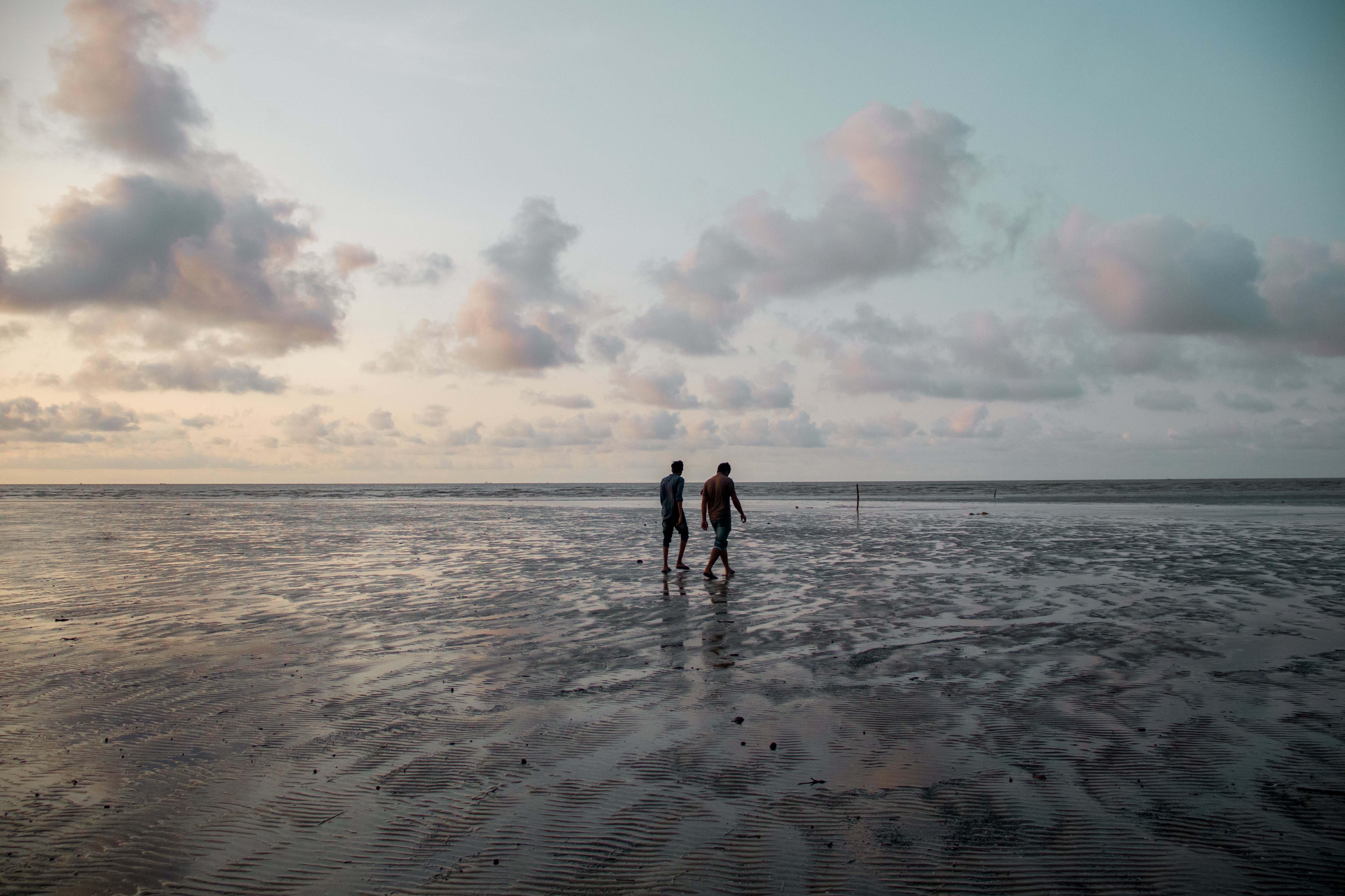 Due persone che camminano lungo la spiaggia al tramonto foto 