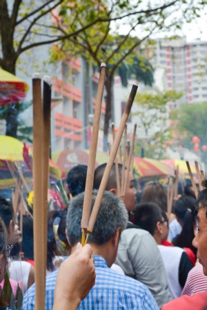 Rua cheia de pessoas segurando varas compridas com pontas queimadas Foto 