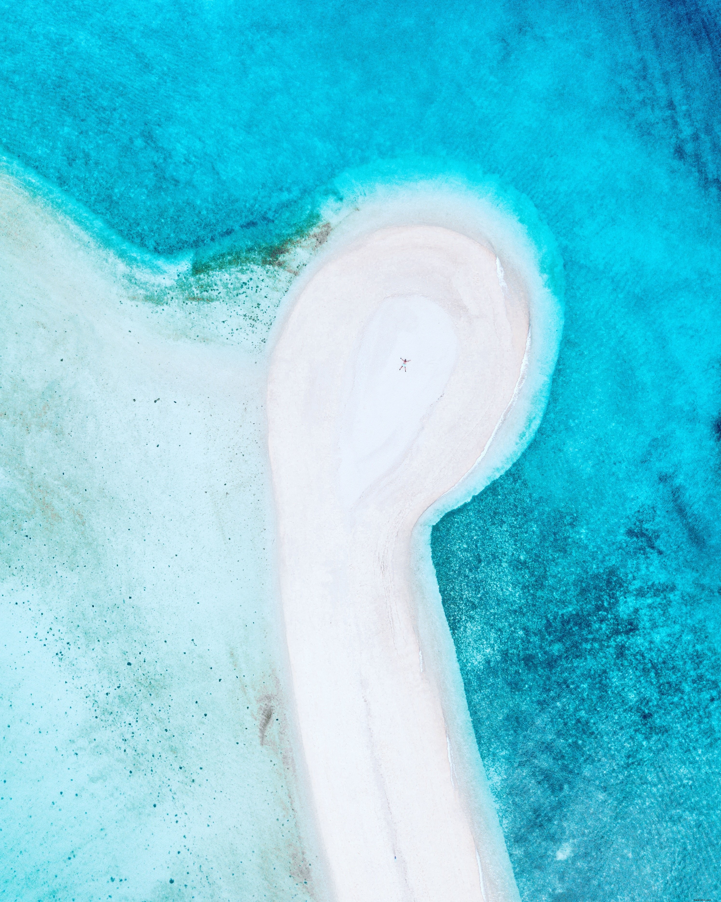 Imagem de drone de pessoa na foto de uma praia de areia branca 