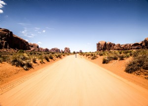 Una figura si trova su una strada nel deserto sotto il cielo azzurro Foto 
