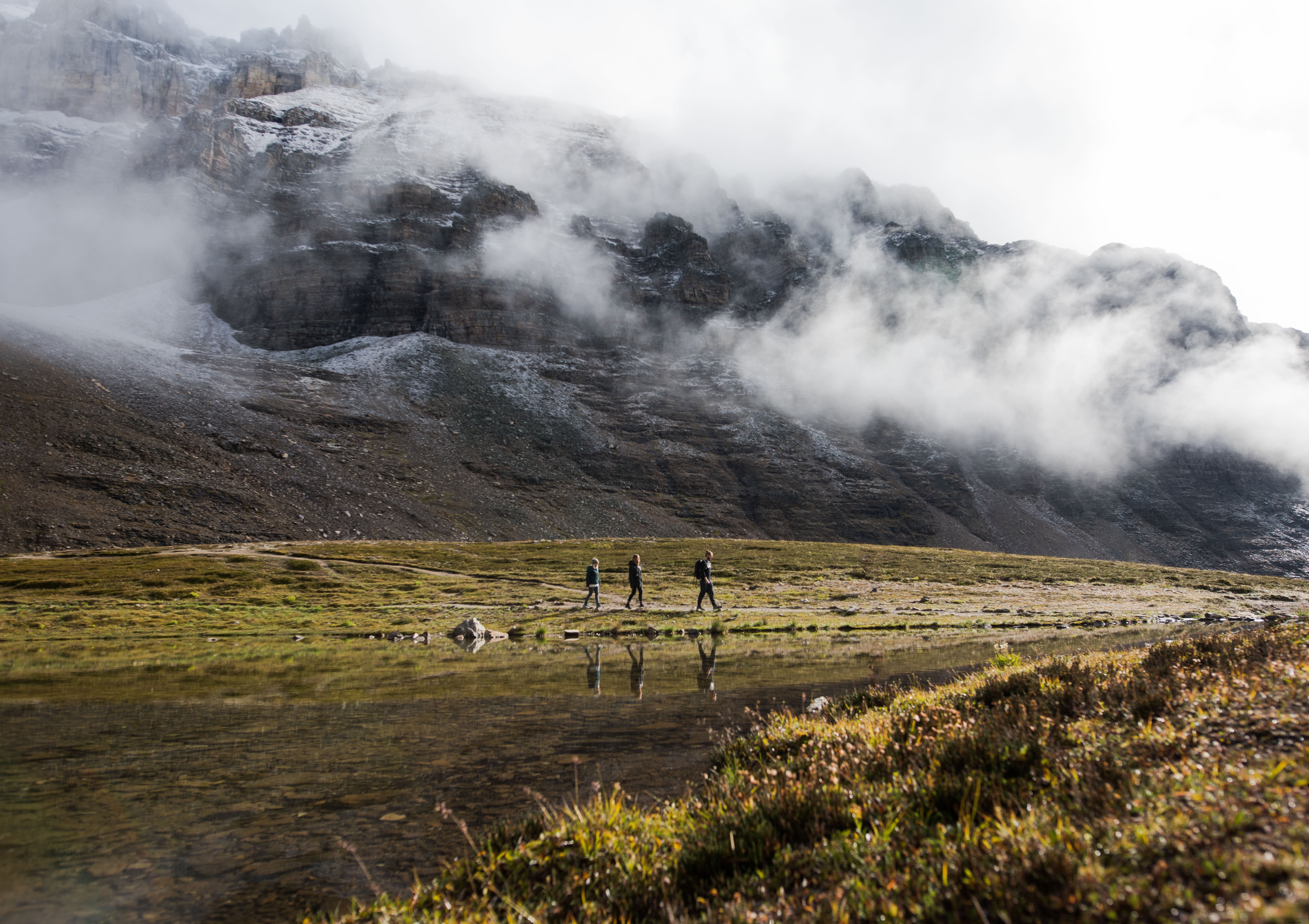 Foto dos caminhantes abaixo das montanhas enevoadas 