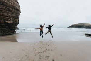 Dua Orang Melompat Tinggi Di Foto Pantai Berpasir 