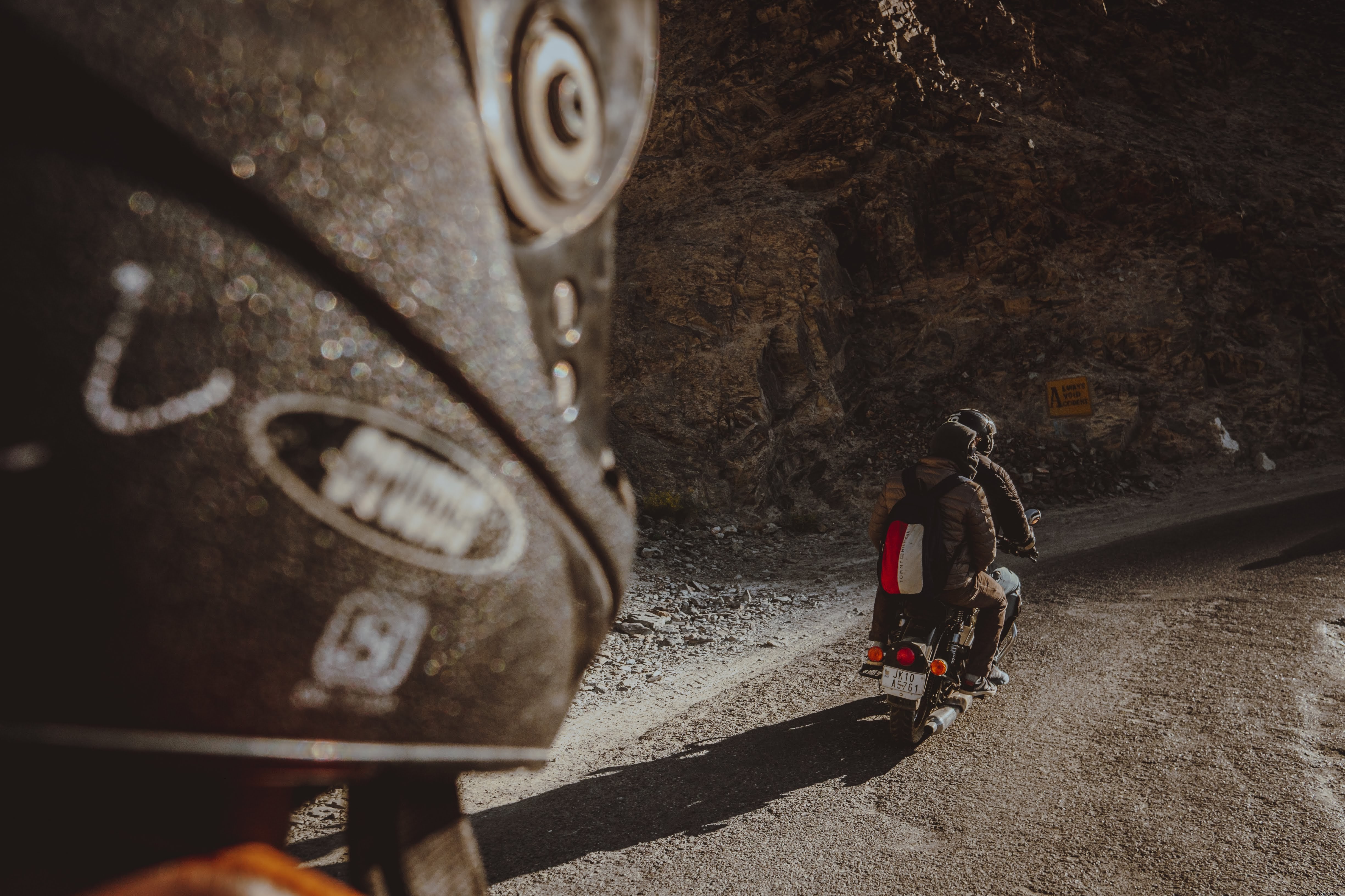 Foto de duas pessoas andando de moto em uma estrada de terra 