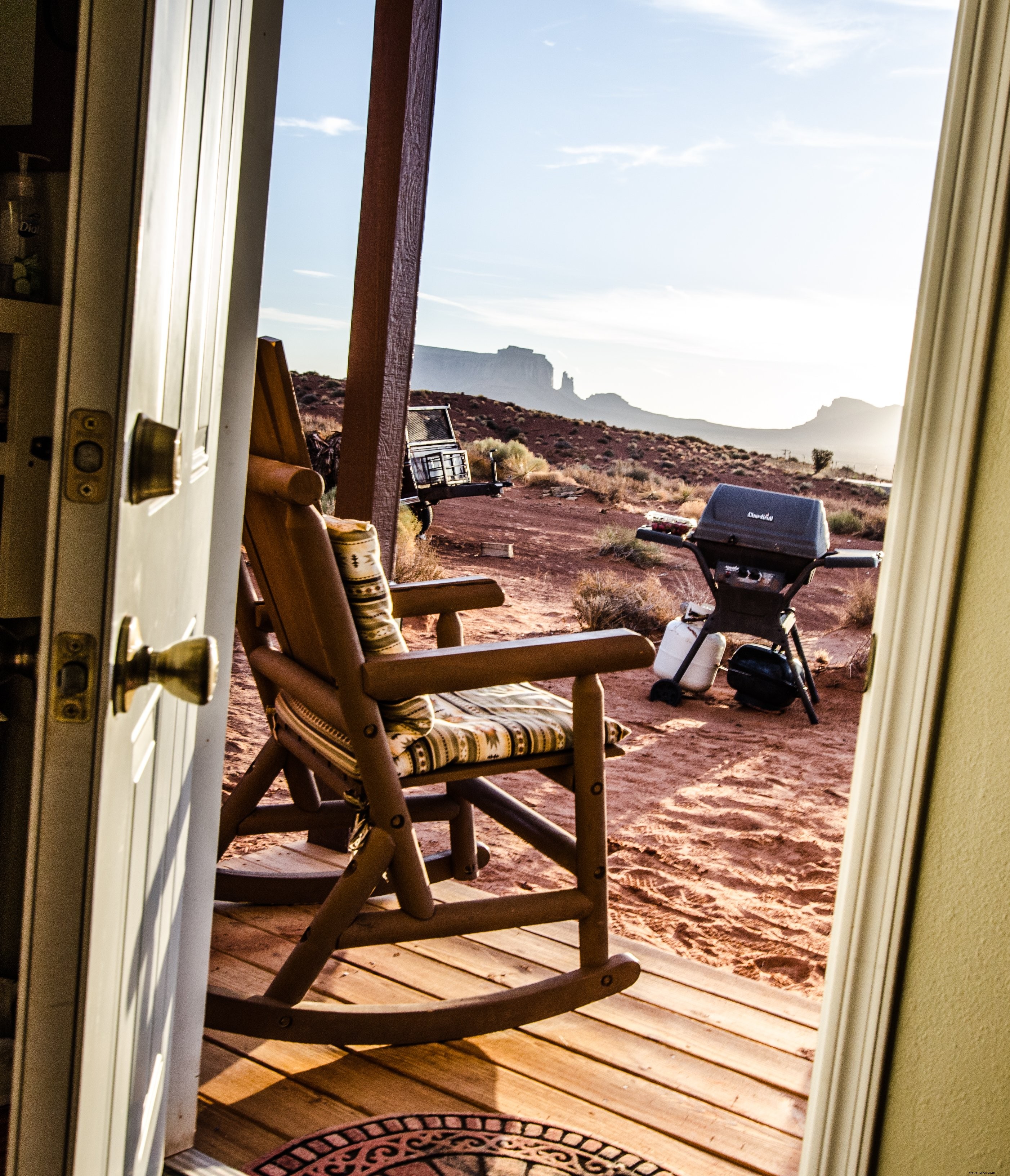 Através de uma porta, uma cadeira de balanço em uma varanda tem vista para o deserto. 