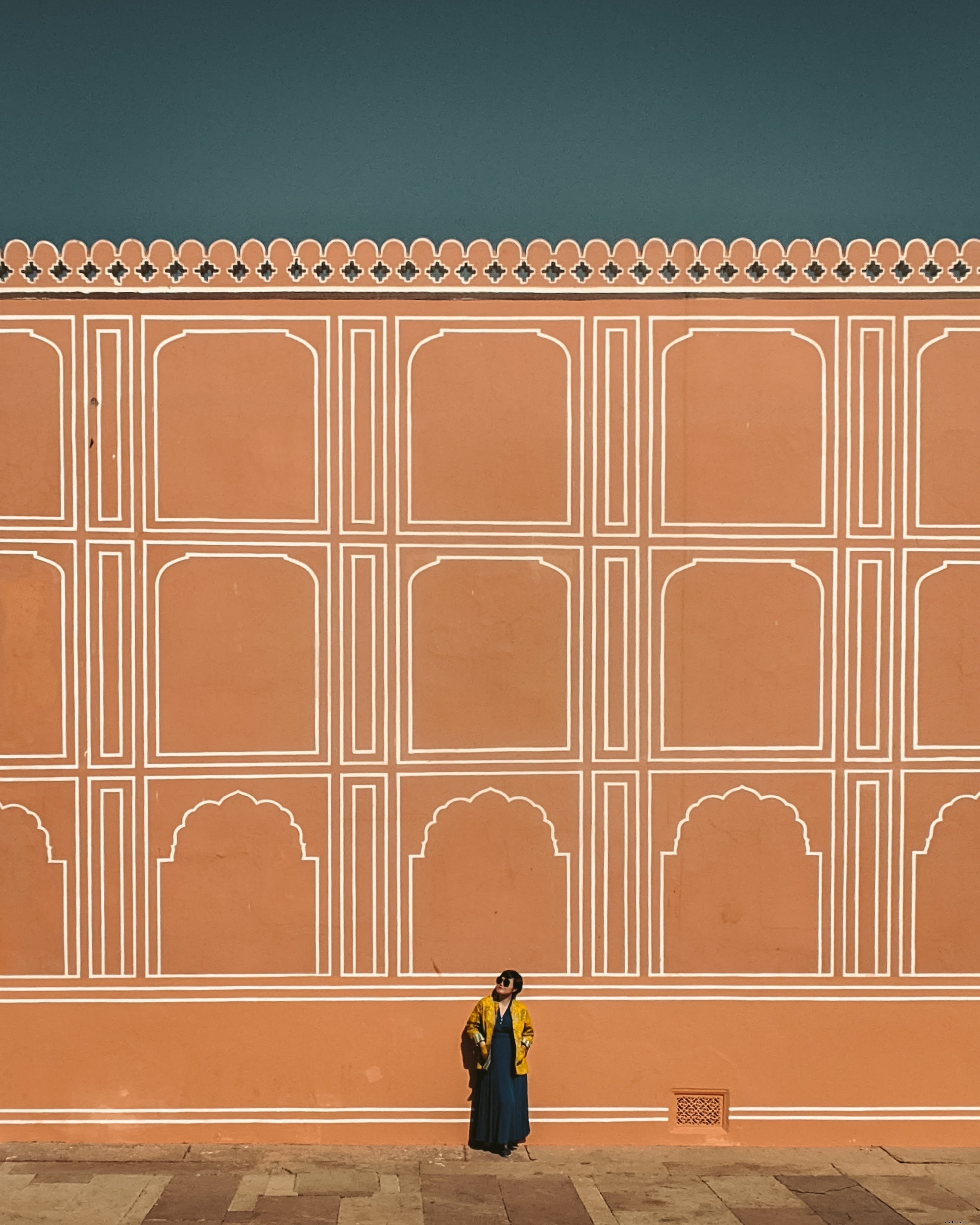 Persona in piedi da un alto muro arancione e cerca foto 