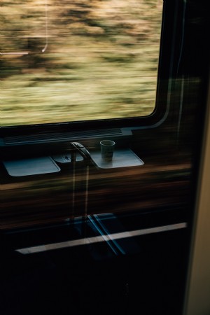 Taza de papel blanco y una maleta en una foto de tren en movimiento rápido 