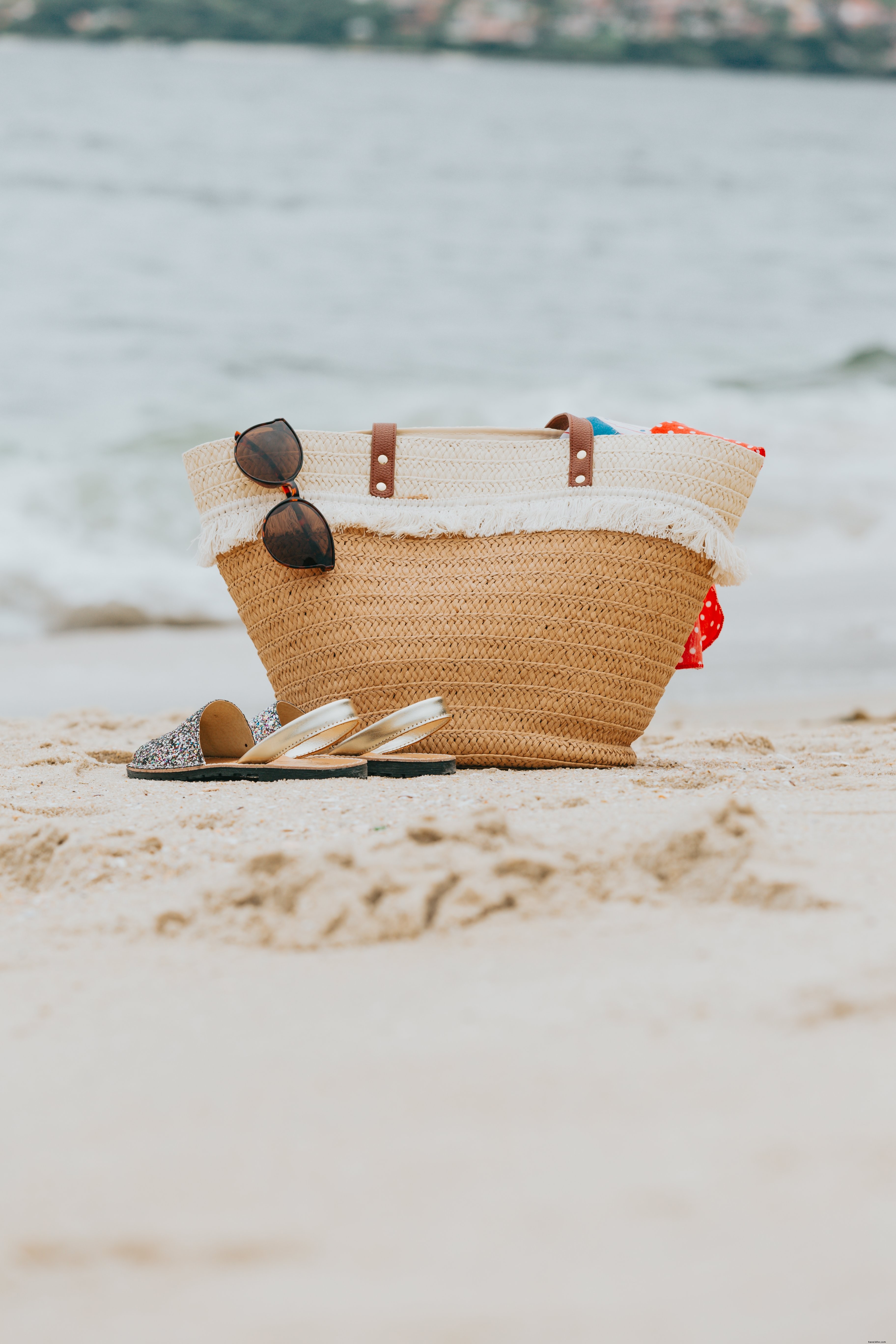 Sac de plage en osier et sandales sur une photo de plage de sable blanc 