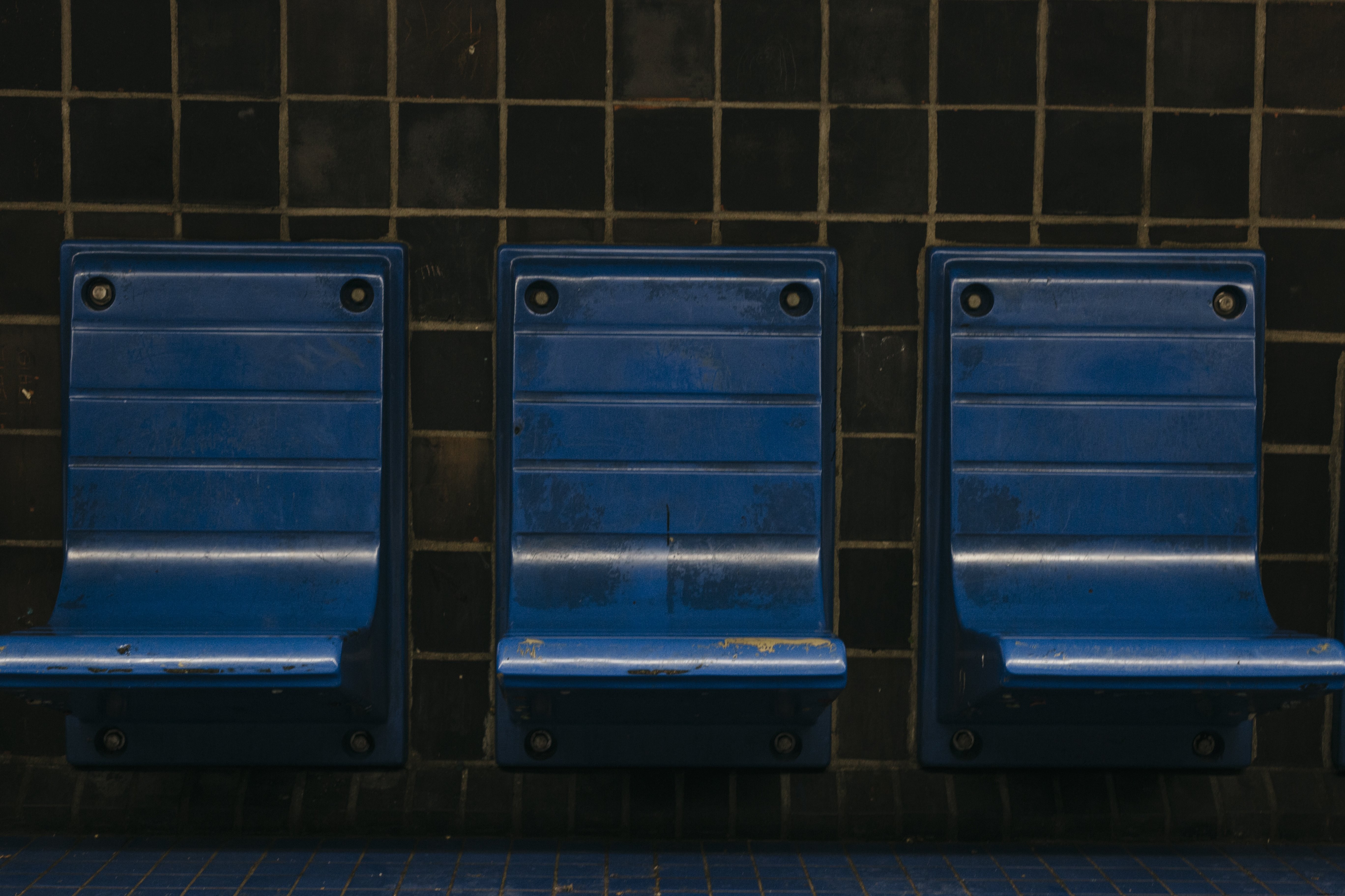 Foto de cadeiras azuis em uma plataforma de metrô 