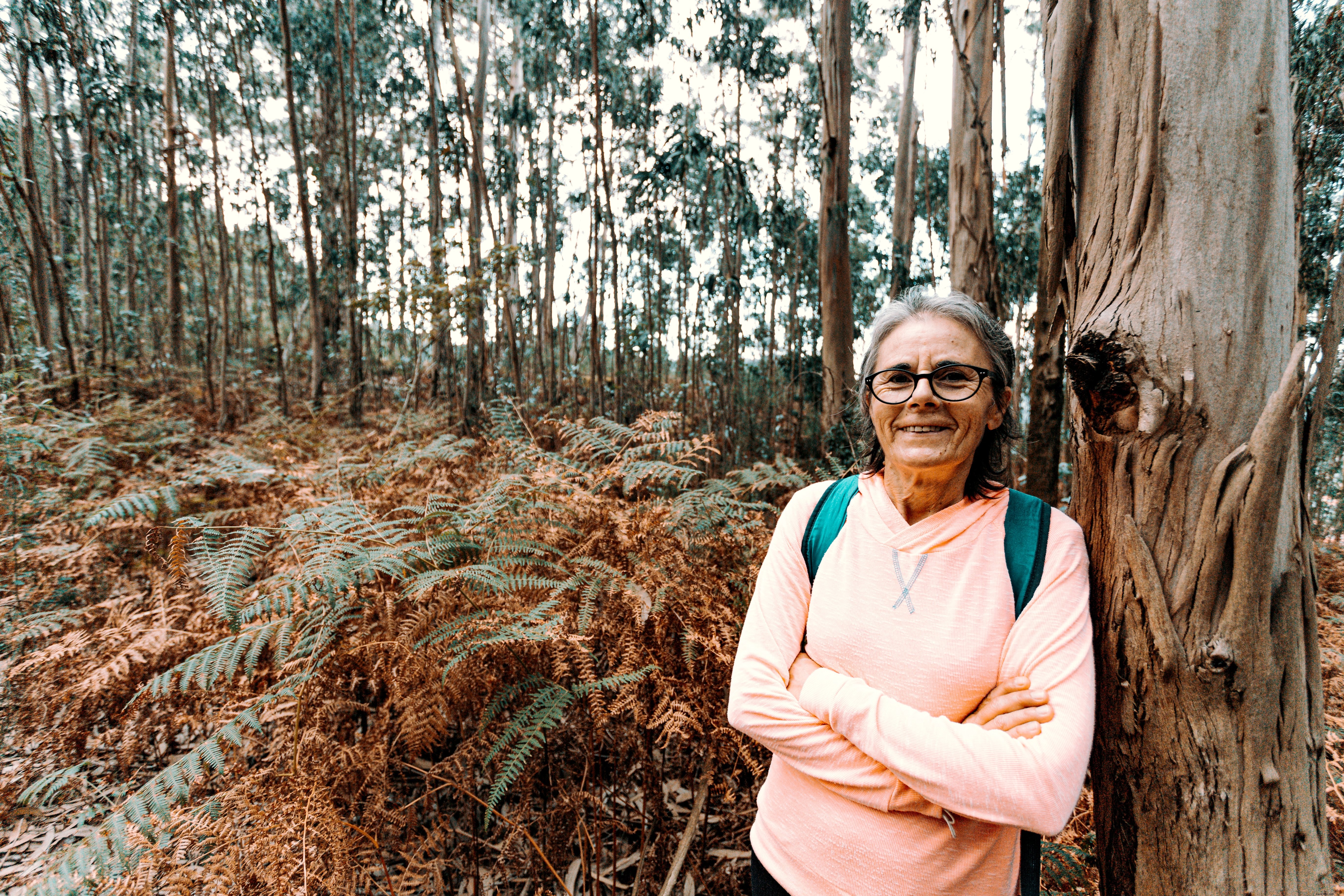 Mulher sorri e se inclina sobre uma grande foto de árvore 