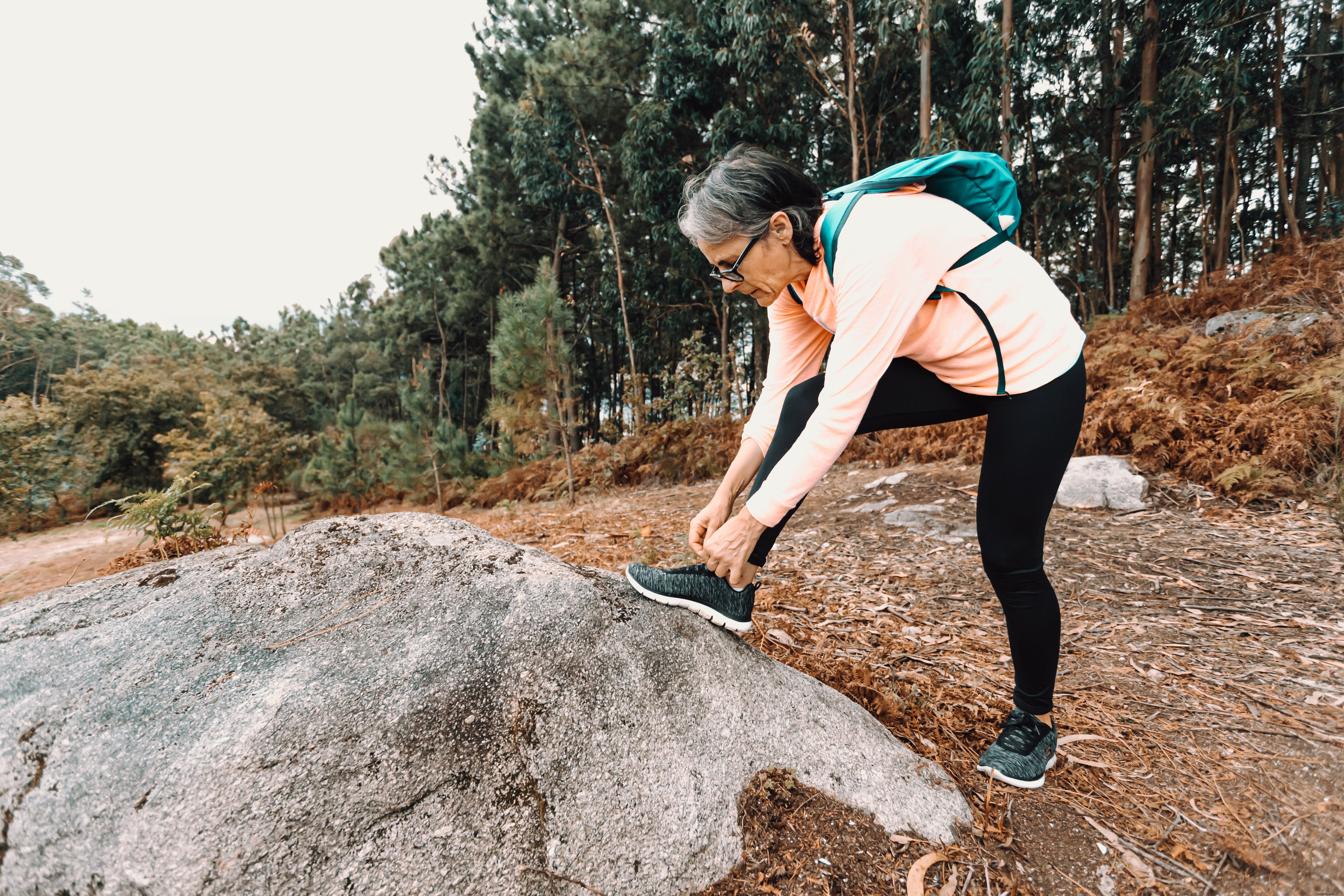 Mulher para em uma caminhada para amarrar o sapato Foto 