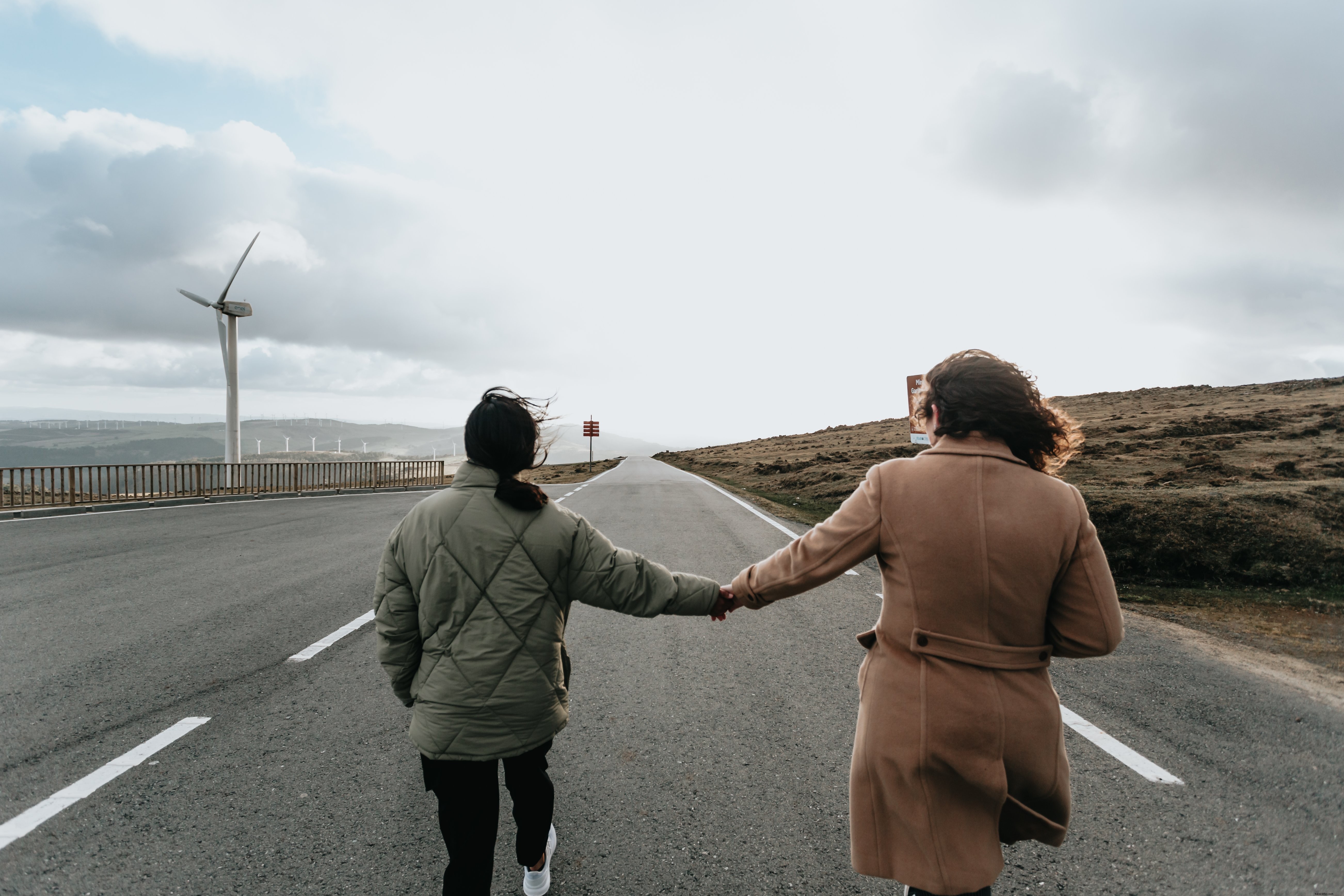 Due persone si tengono per mano e camminano lungo una strada asfaltata Photo 