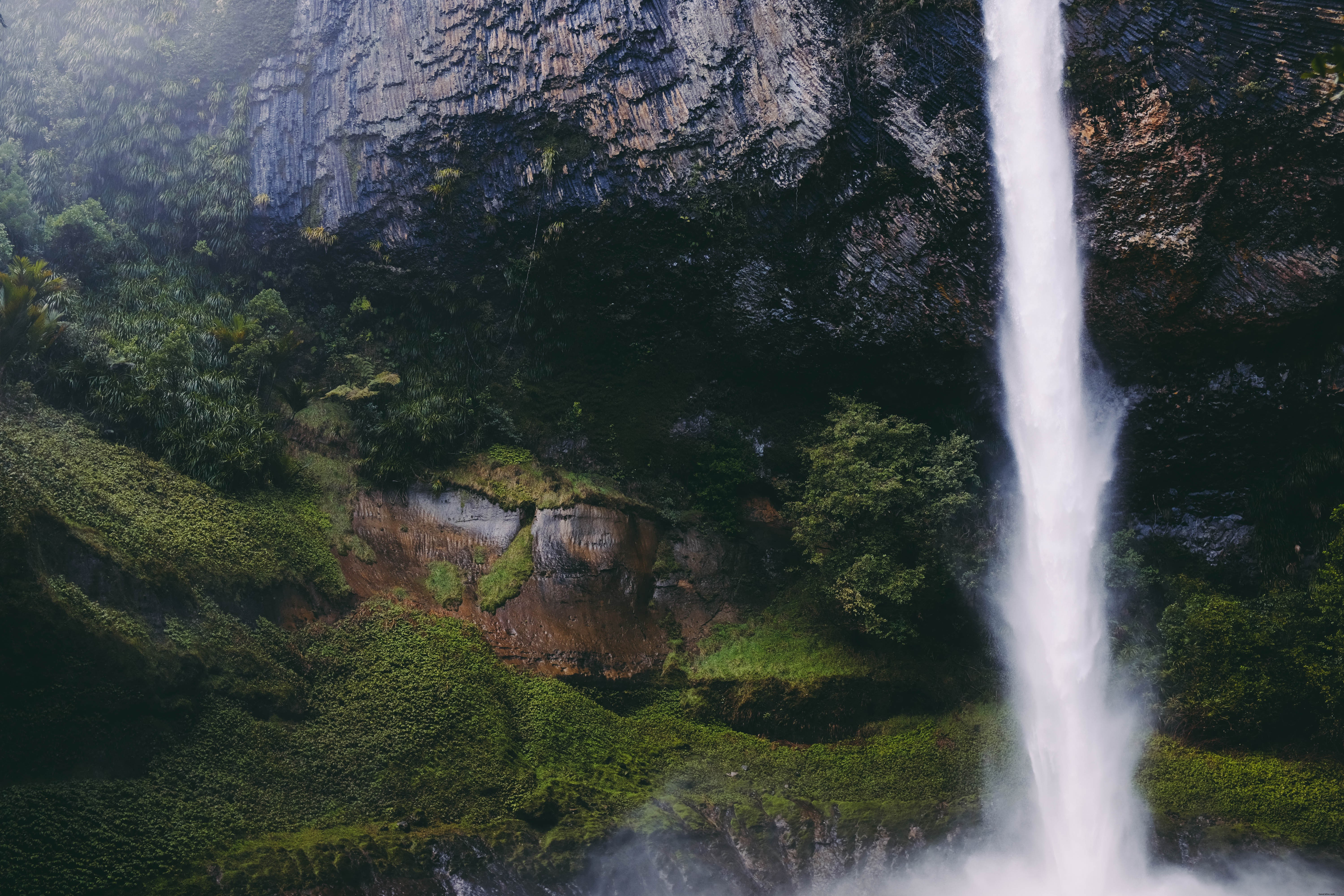 Cachoeira de formações rochosas sobre a grama 