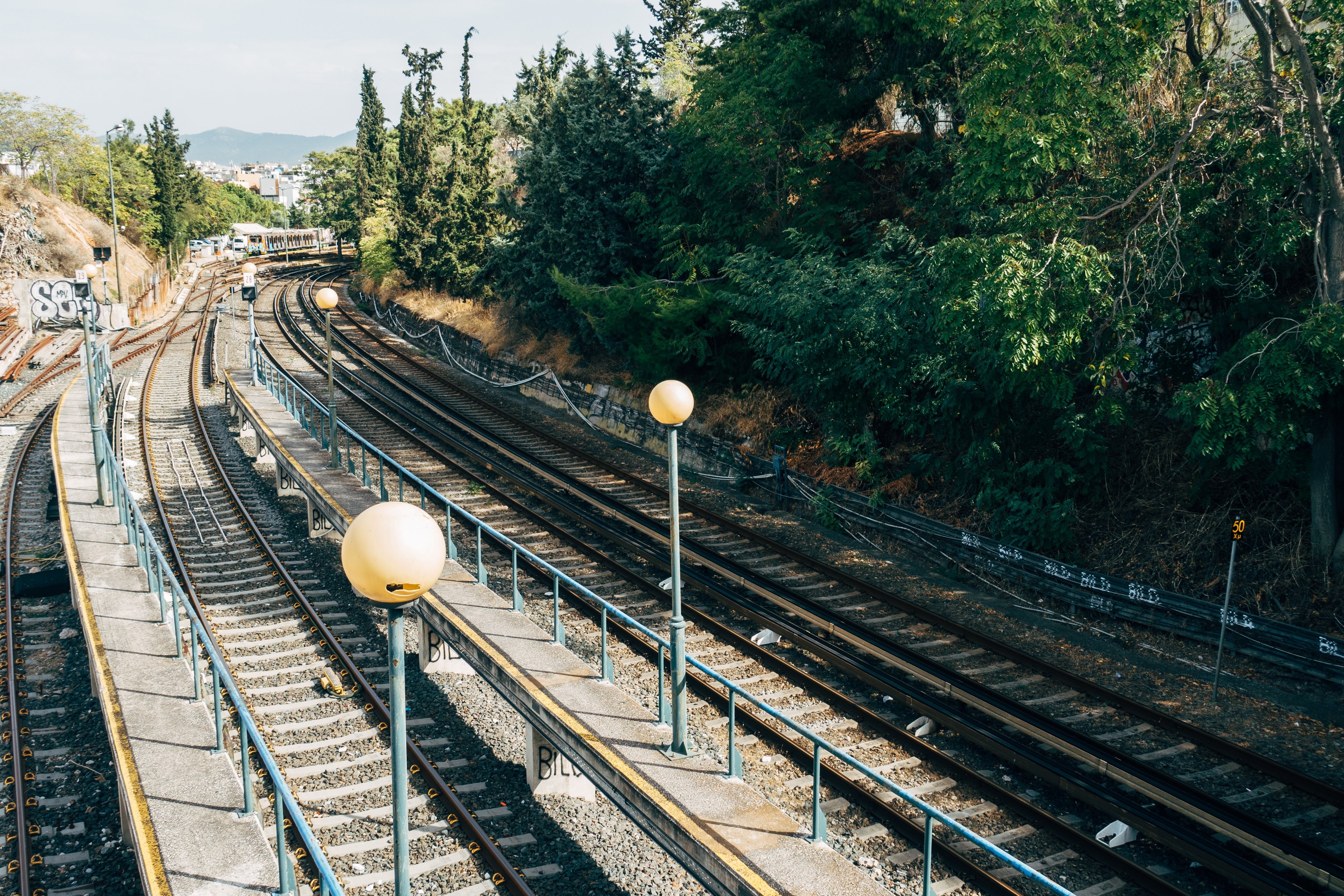 Foto de trilhas de trem alinhadas com árvores verdes 