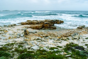 Foto de olas de un azul profundo rompiendo contra las rocas 