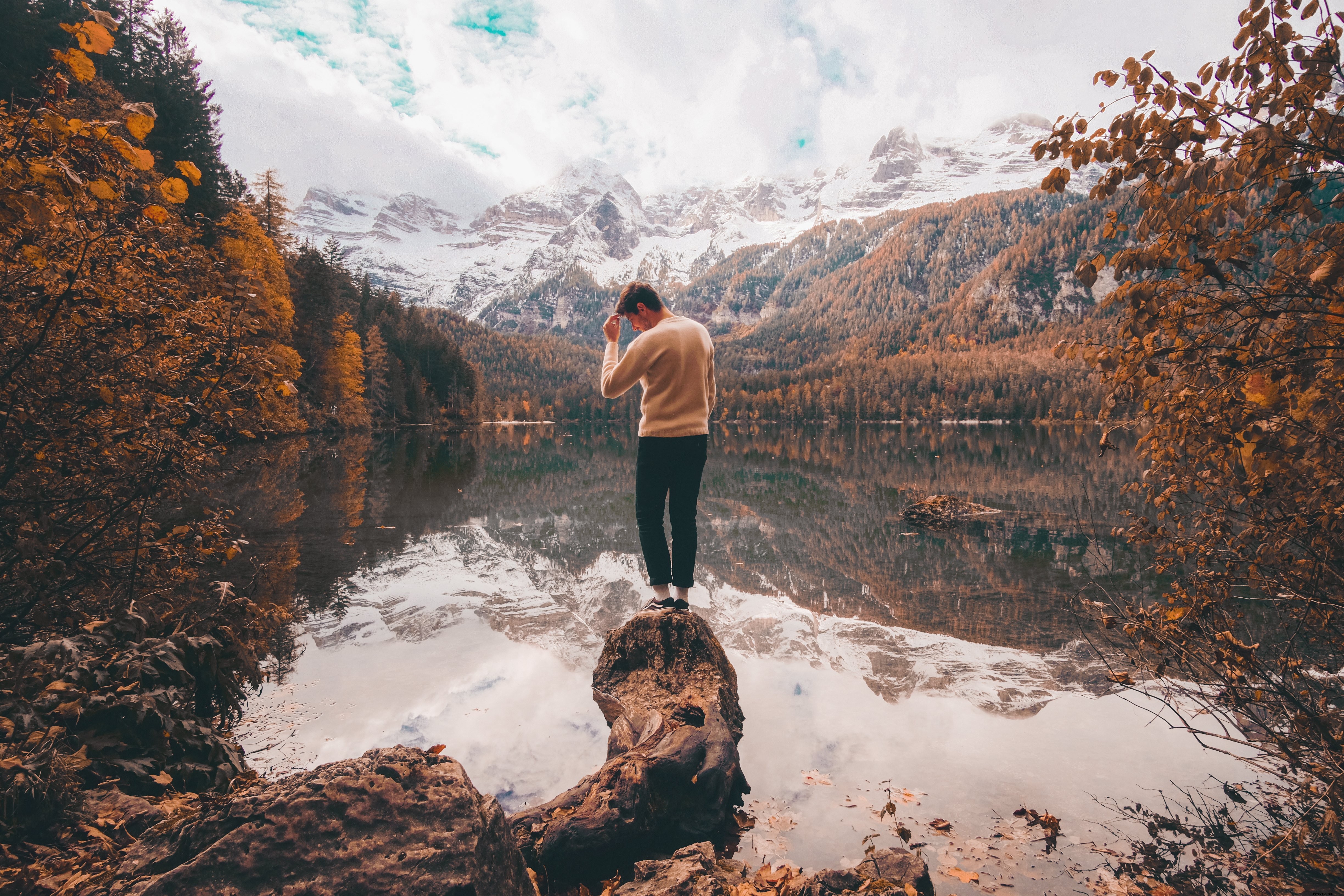 Foto de pessoa cercada por cores do outono e montanhas cobertas de neve 