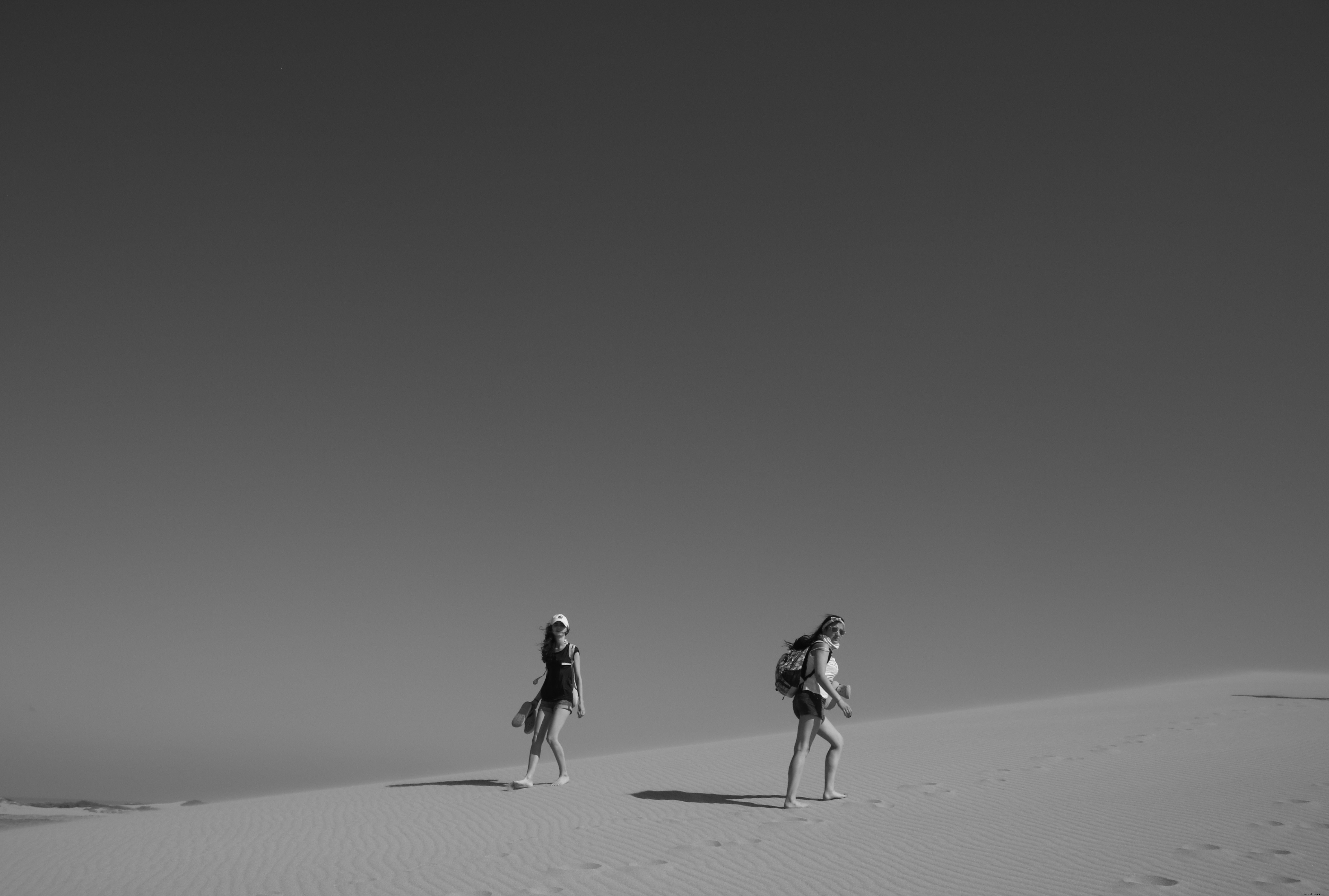 Personnes marchant dans le désert en photo noir et blanc 