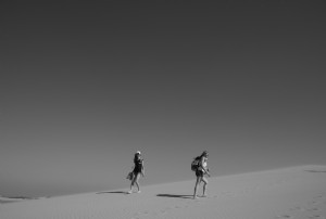 Personnes marchant dans le désert en photo noir et blanc 