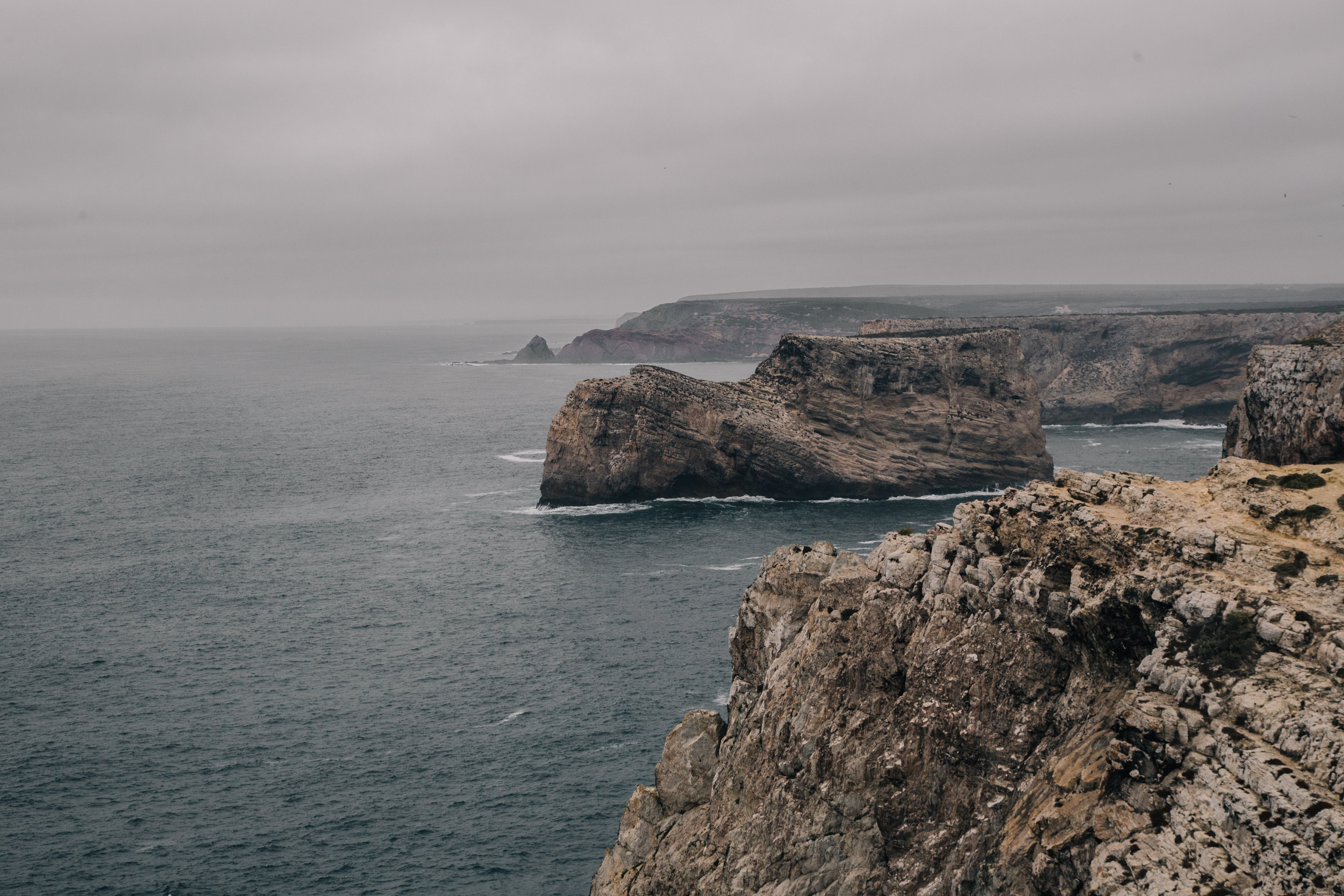 Los acantilados rocosos retroceden desde el frío mar gris Foto 