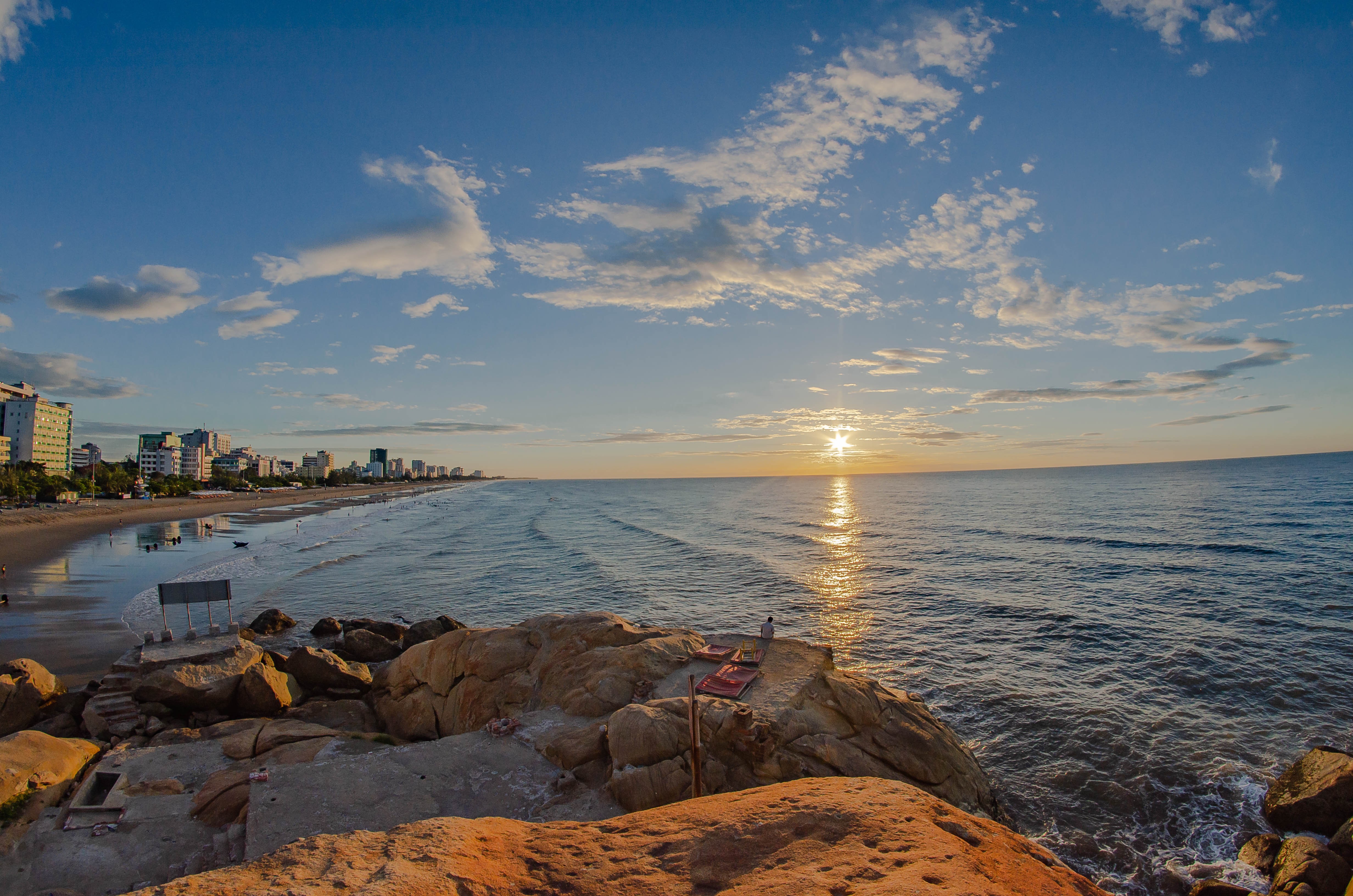 O pôr do sol sobre as águas paradas em uma foto da costa da cidade 