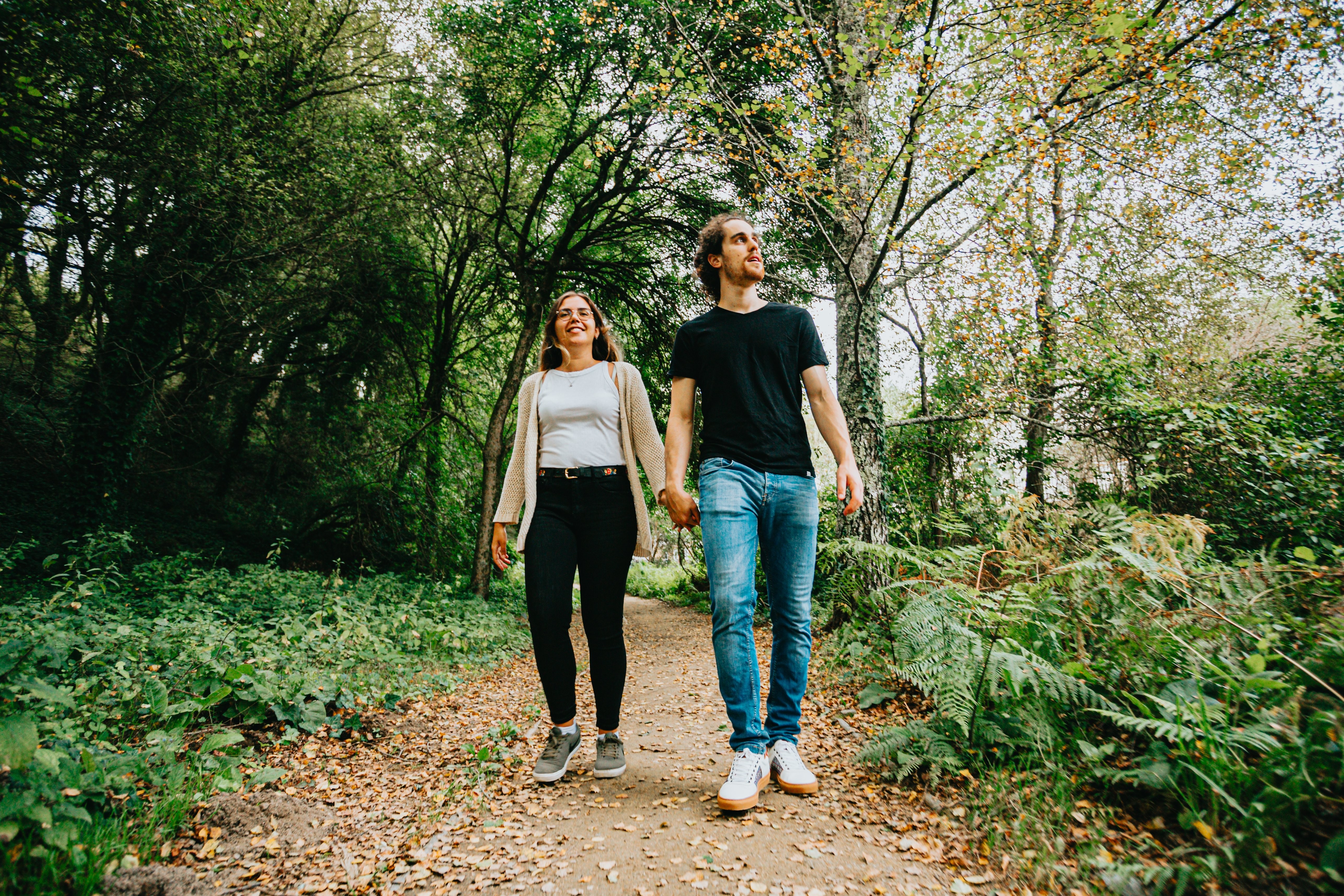 Foto de homem e mulher de mãos dadas em uma floresta 