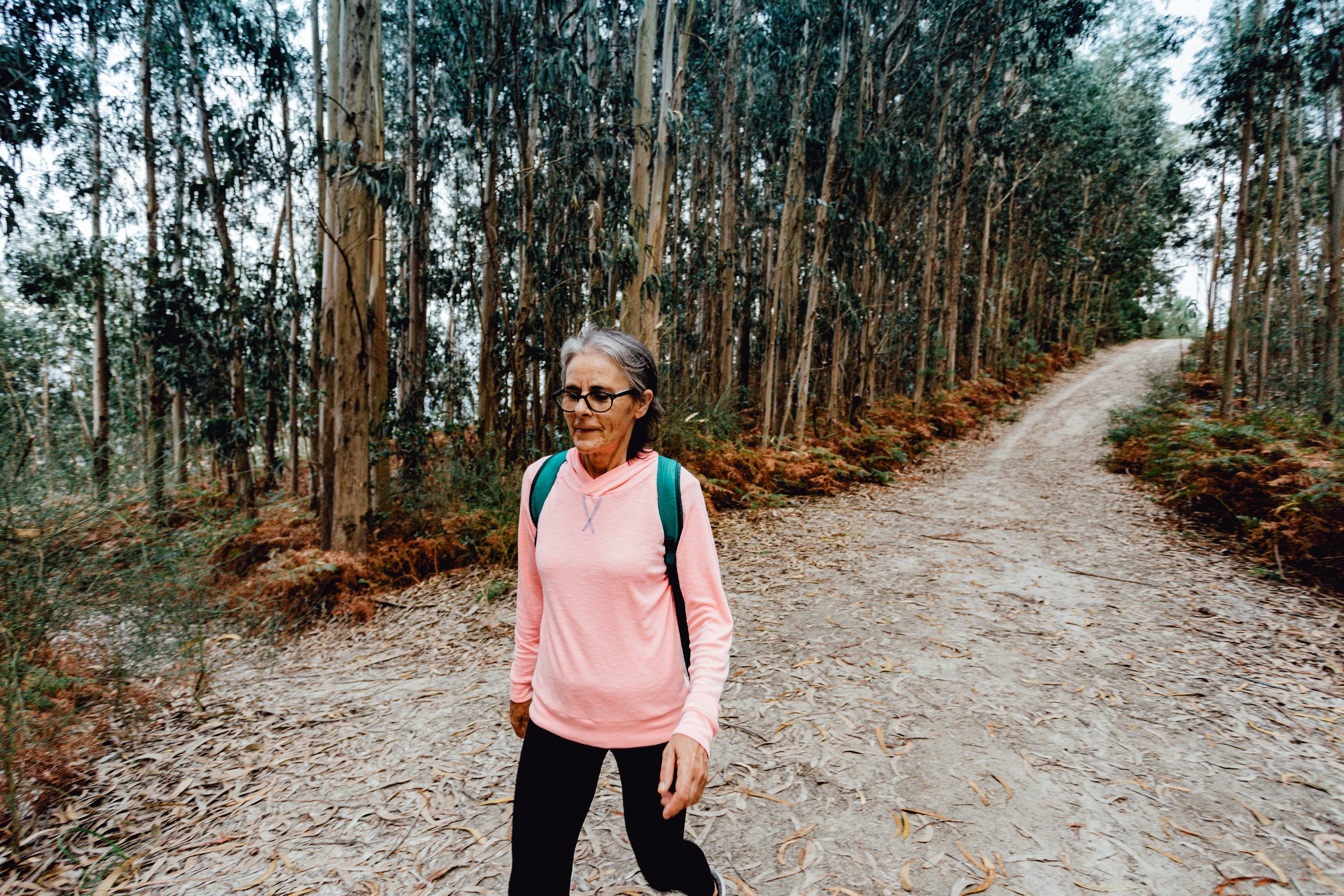 Mulher desce em um caminho ladeado por árvores, foto 