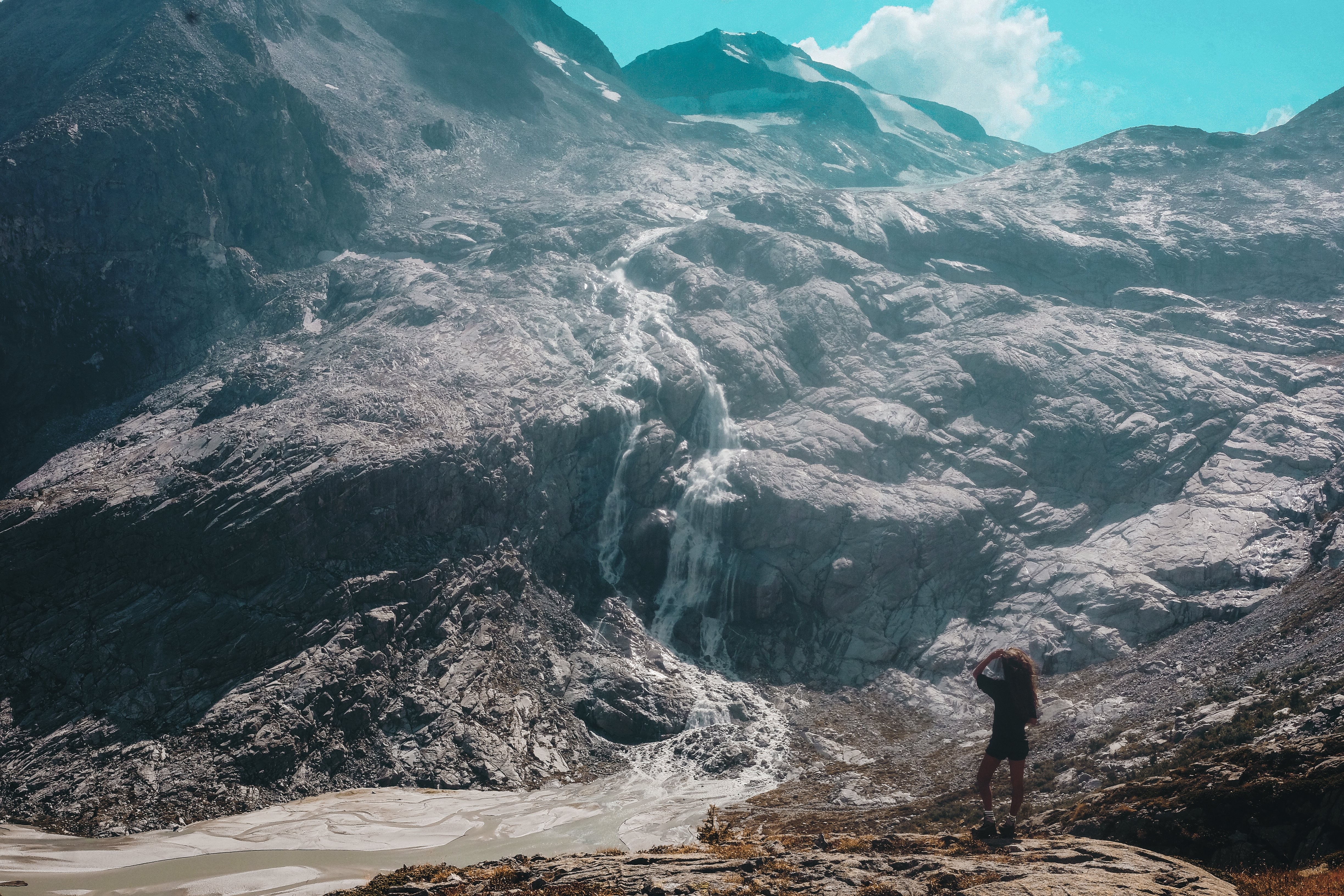 Persona mira hacia arriba para ver una foto de una cascada en la ladera de la montaña 