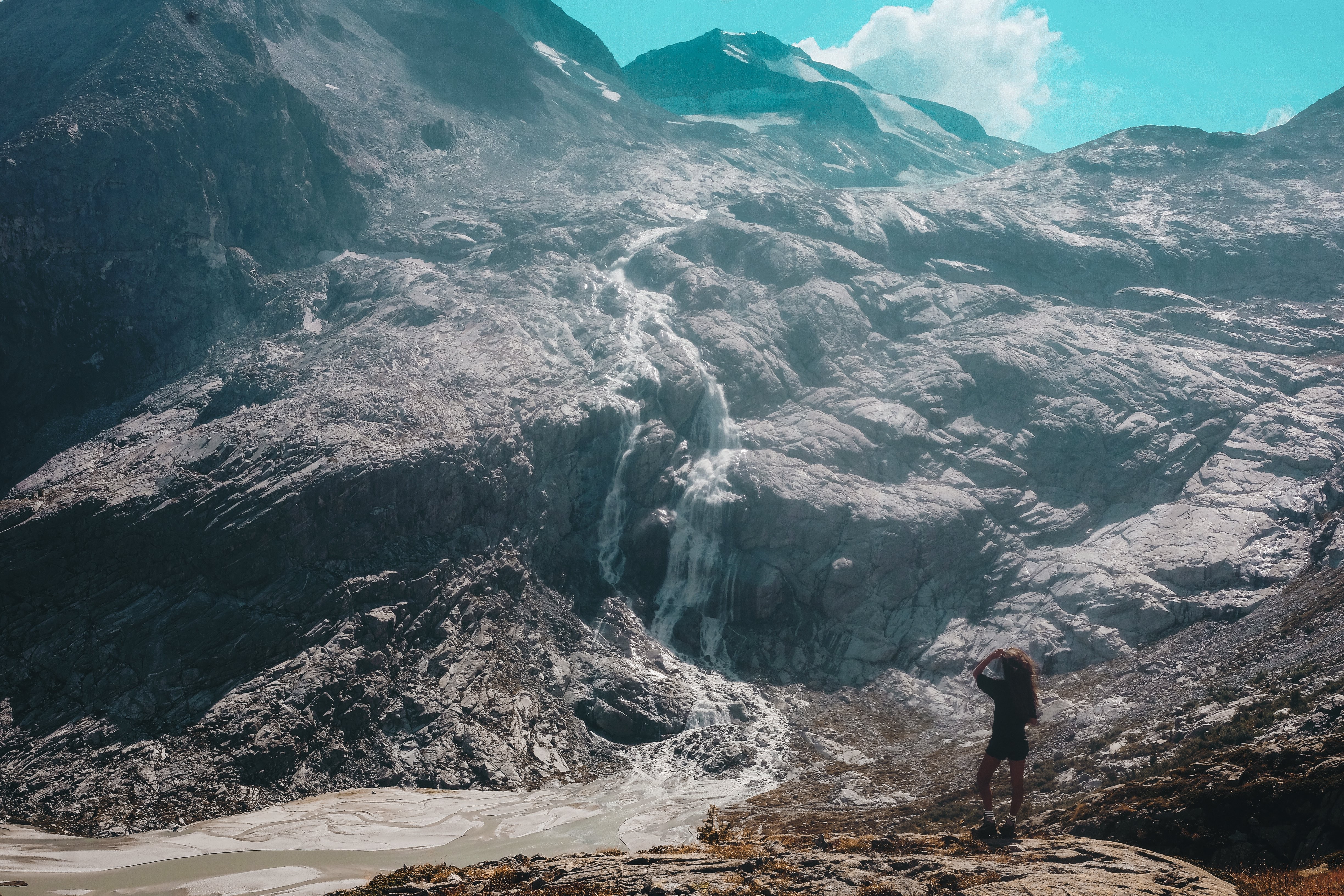 Pessoa olha para cima para ver uma foto de uma cachoeira na montanha 