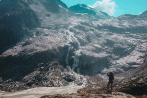 Persona mira hacia arriba para ver una foto de una cascada en la ladera de la montaña 