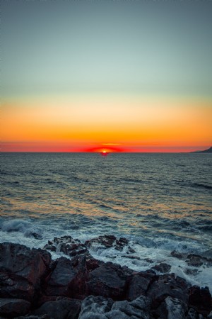 Fotos de los últimos momentos de una puesta de sol sobre la costa rocosa 