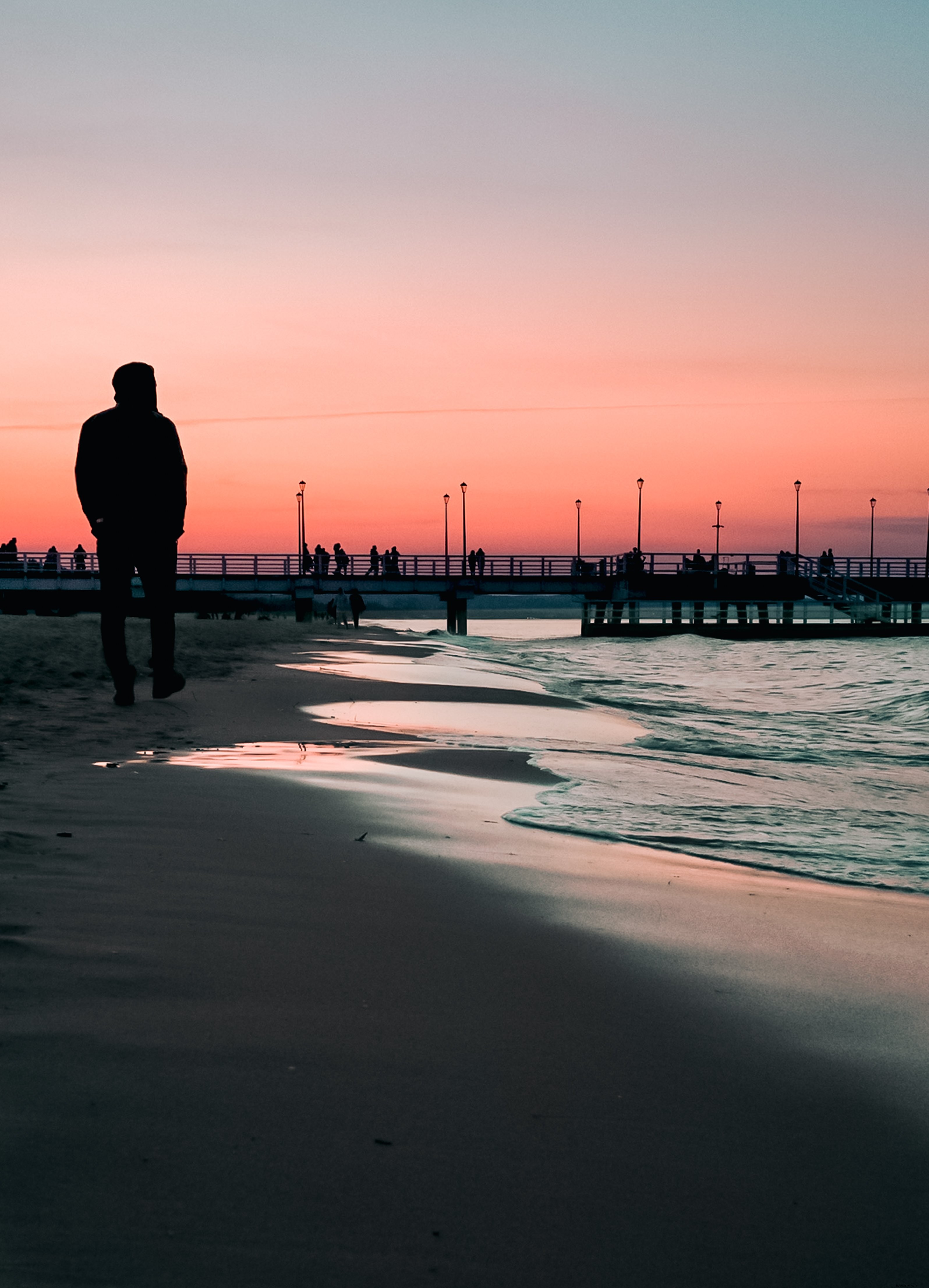 Passeggiata sulla spiaggia al tramonto con un molo in lontananza Photo 