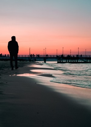 遠くの桟橋と夕日のビーチウォーク写真 