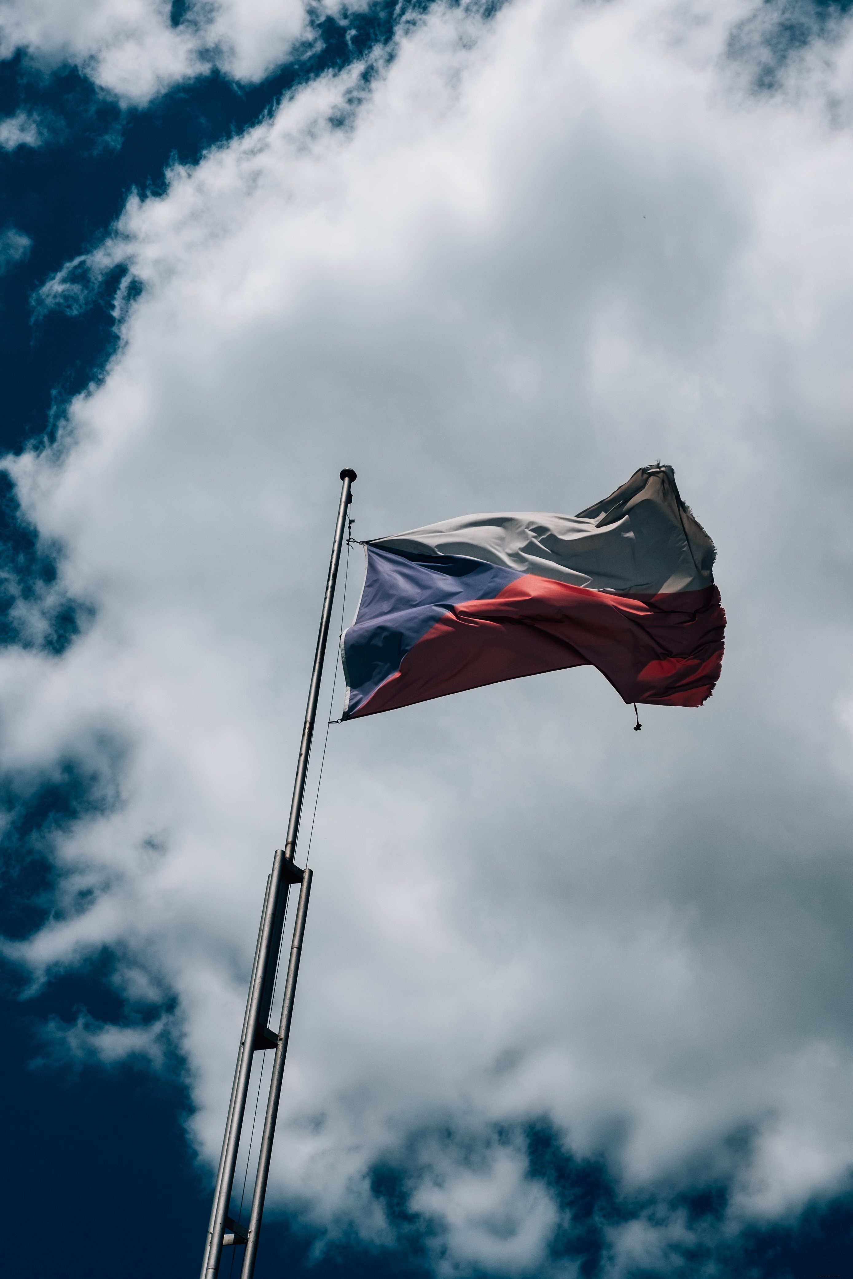 チェコの旗は曇りの青い空の写真に対して飛ぶ 