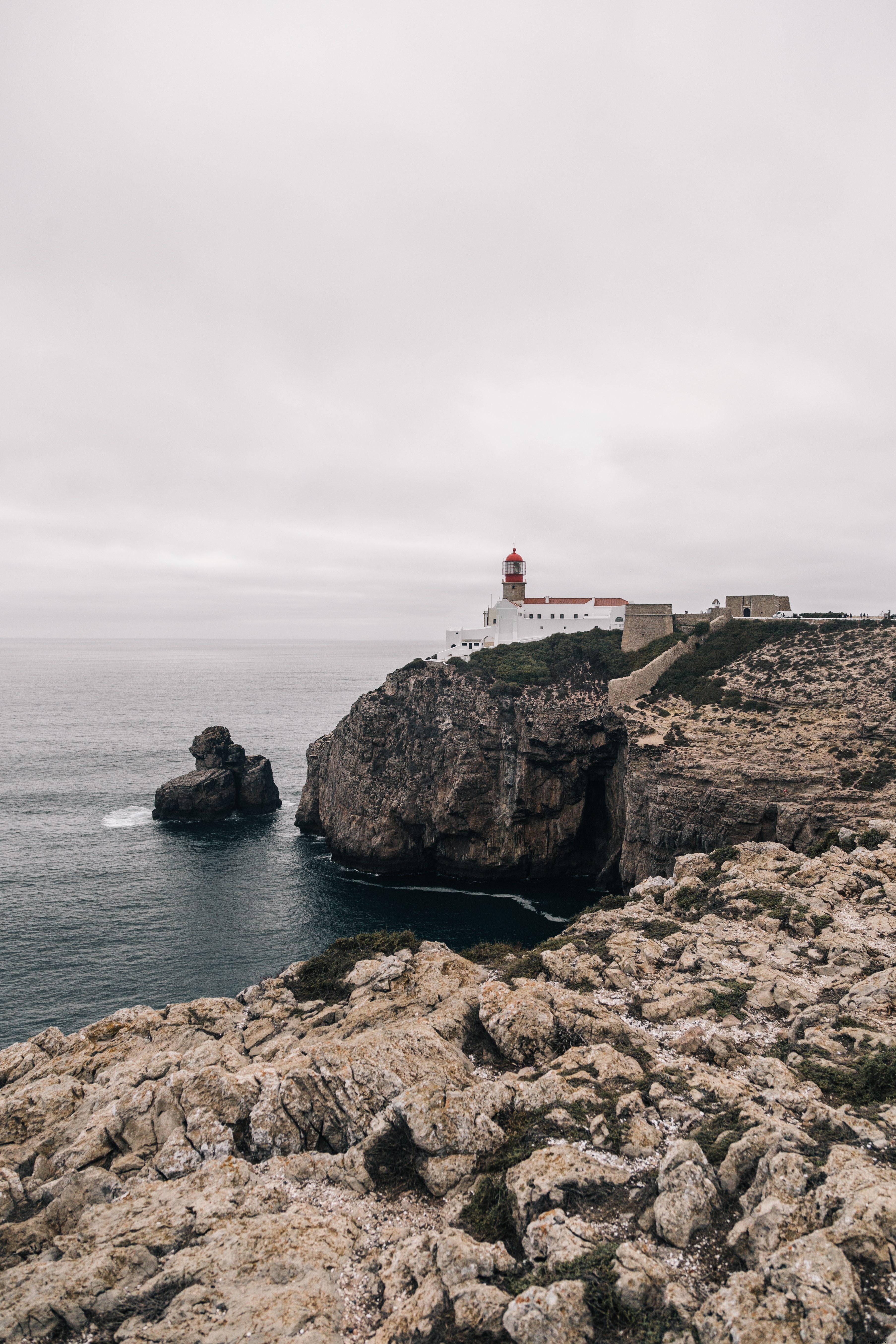 灯台が岩の多い海岸線の写真を見守る 