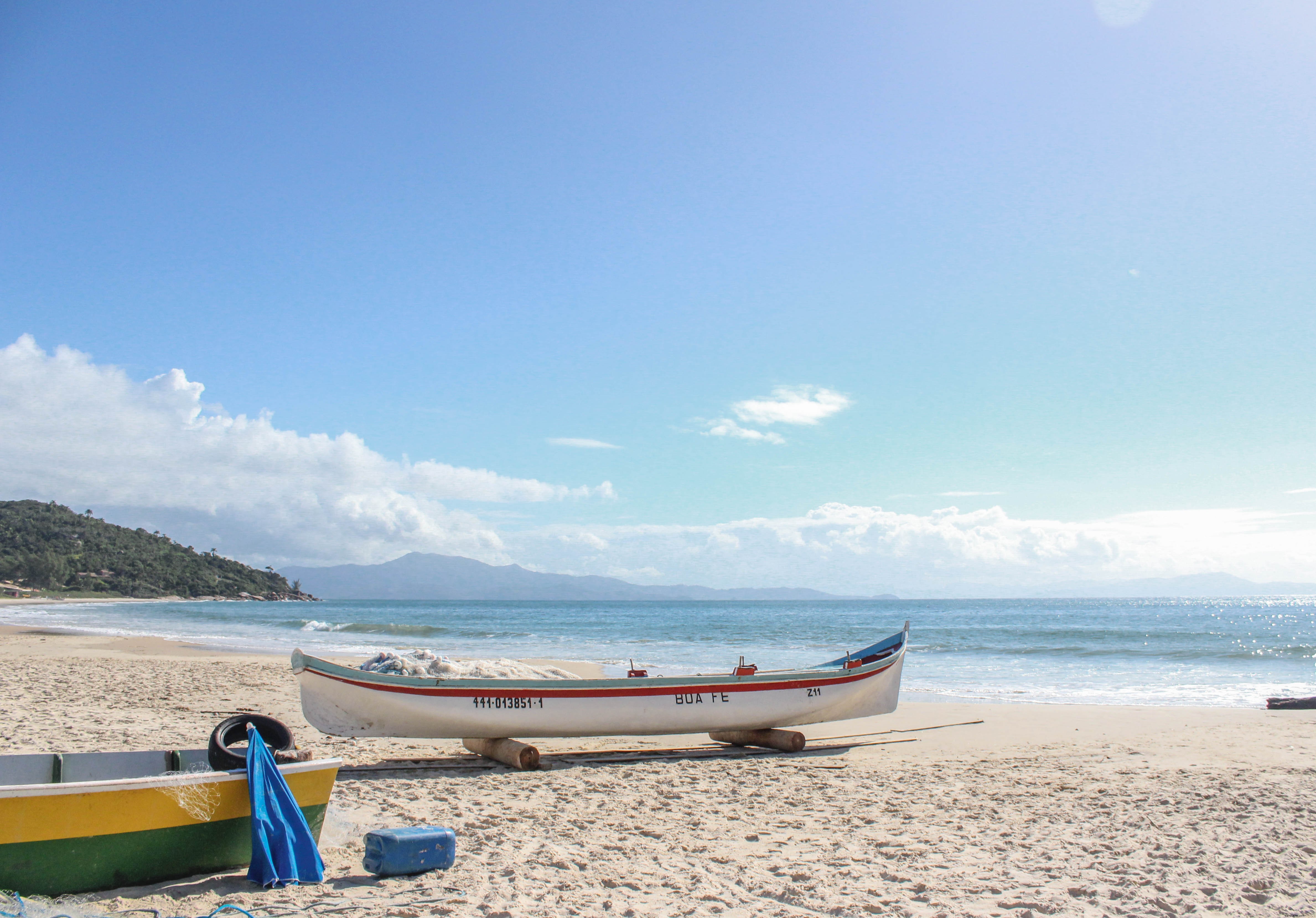 Barco branco com uma listra vermelha em uma foto de praia de areia 