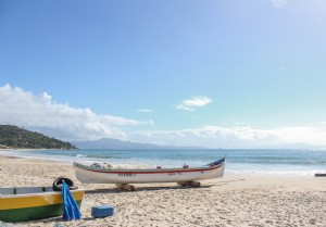 Barco branco com uma listra vermelha em uma foto de praia de areia 
