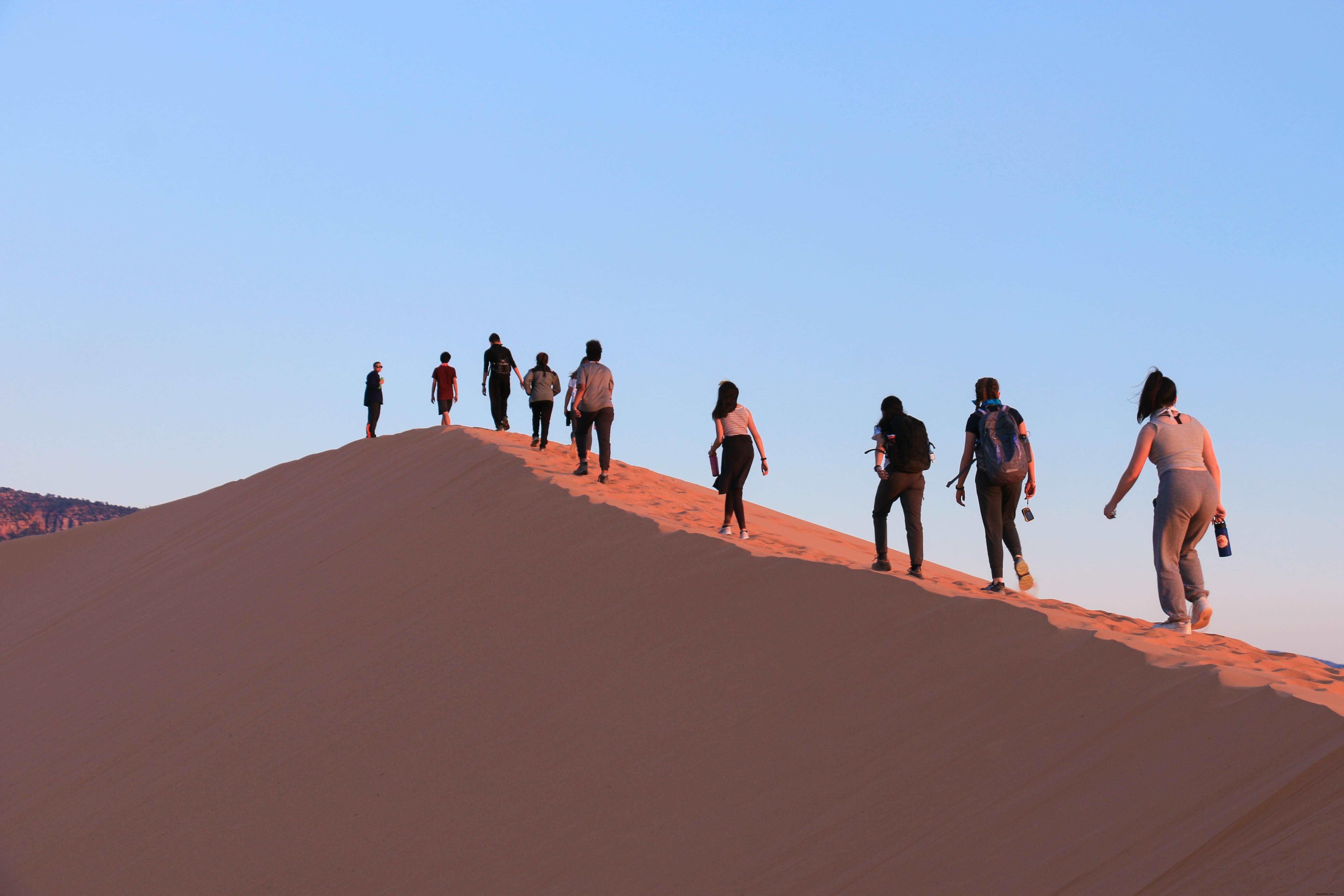 Turistas subindo em uma duna de areia íngreme foto 