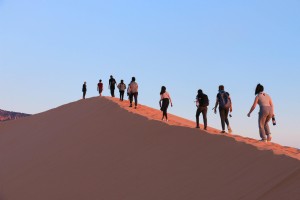 Los turistas suben la empinada foto de una duna de arena 