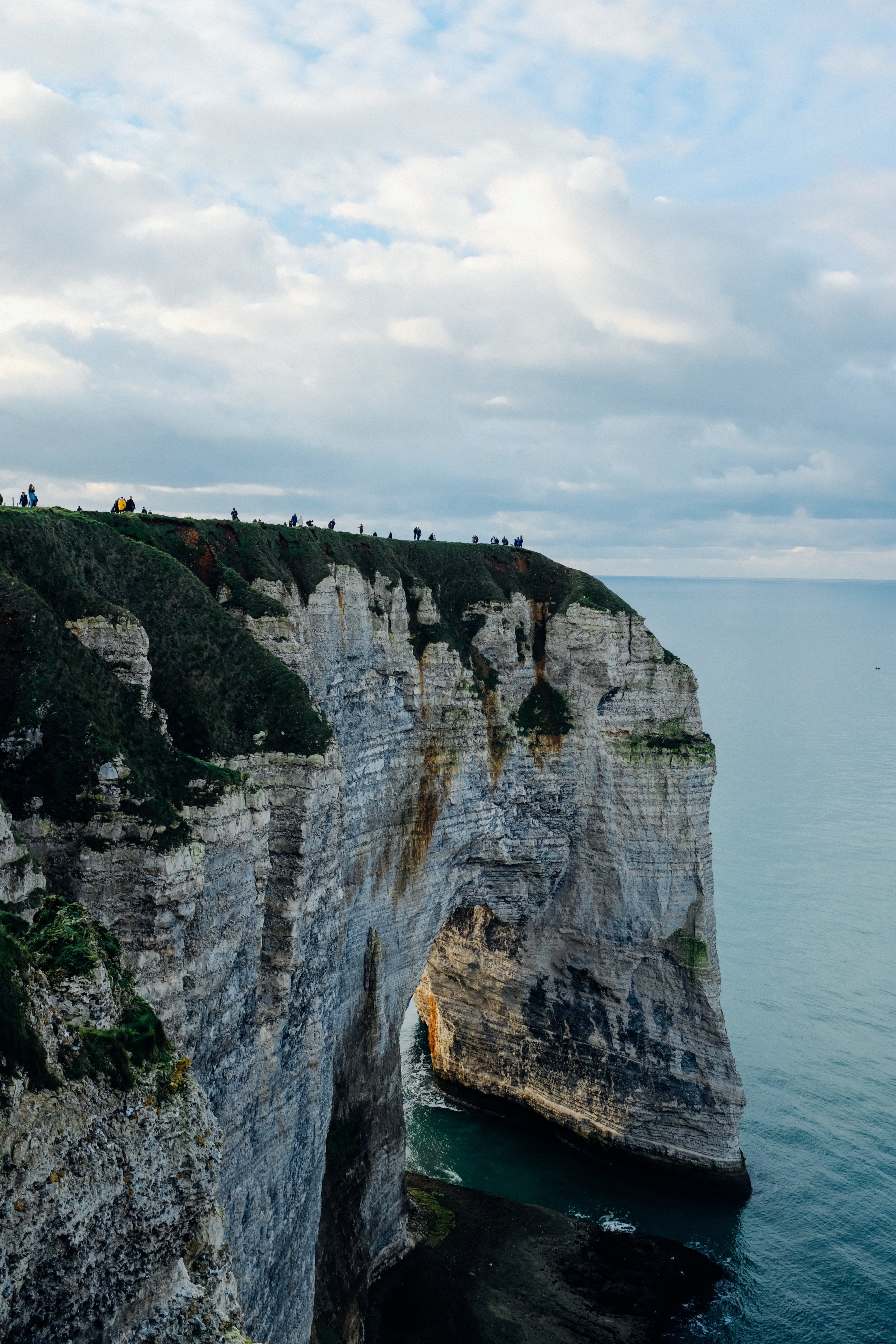 Grande roccia con una cima erbosa si affaccia sull oceano foto 