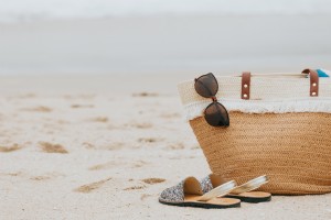 Praia de areia com sandálias de óculos de sol e uma foto de bolsa de praia 