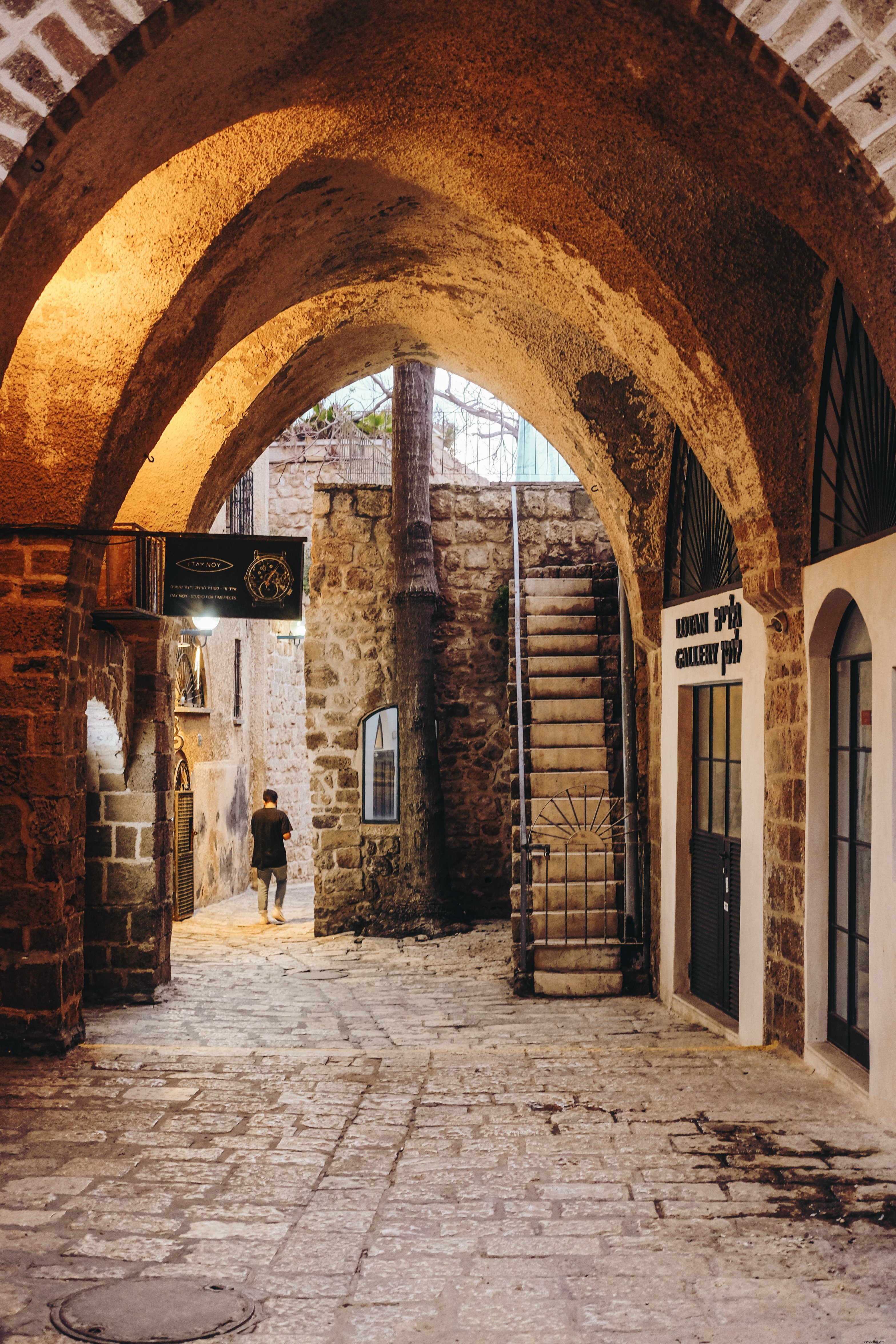 Arco de pedra cobre uma passagem com foto de uma pessoa à distância 