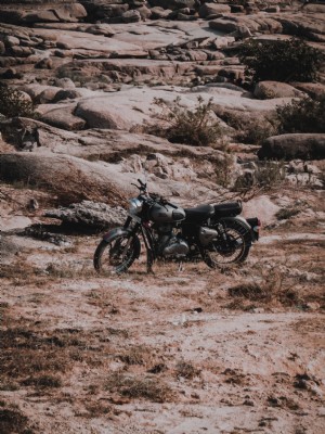 写真の後ろに石の丘が駐車された黒いオートバイ 