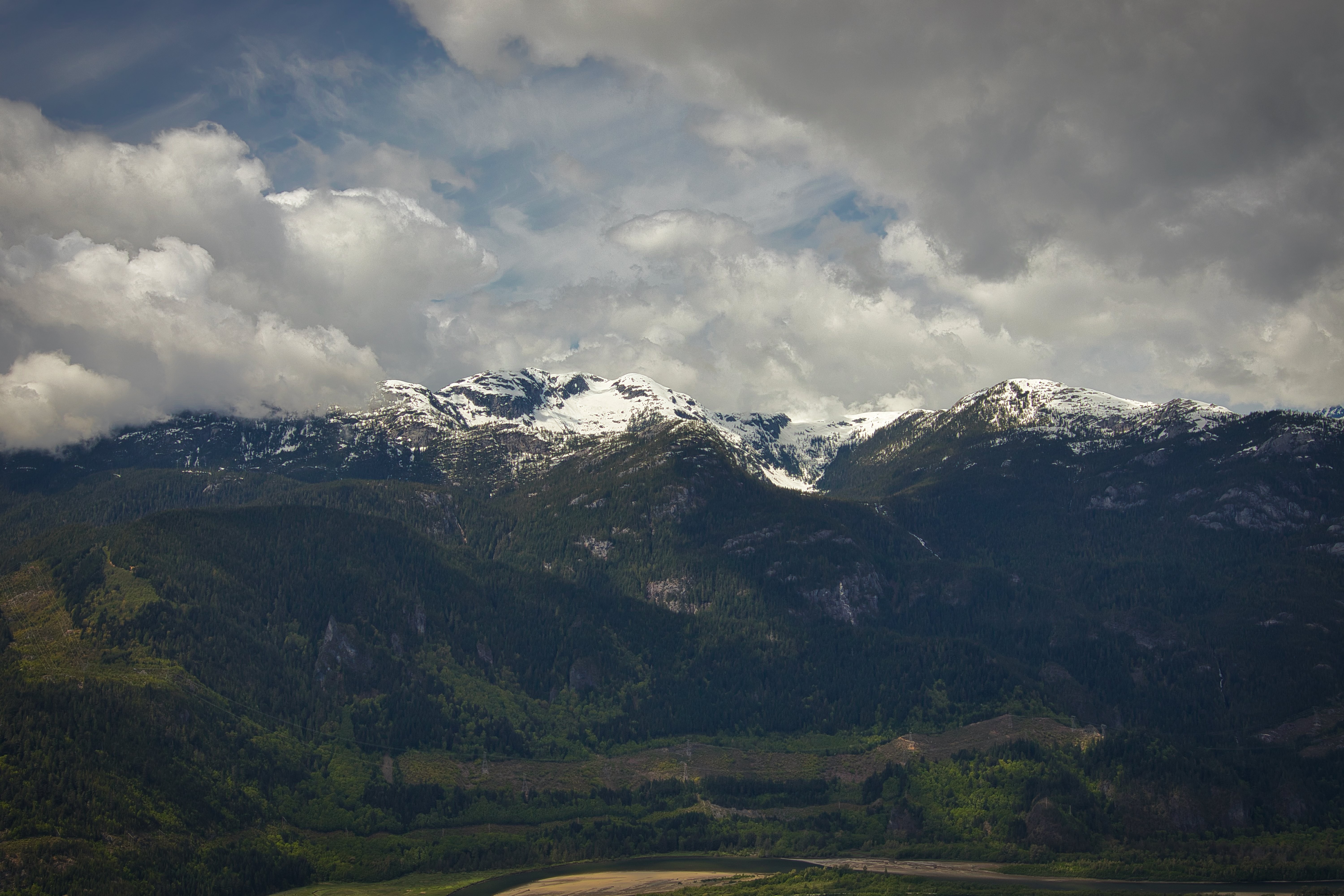 Foto de montanhas verdes cobertas de neve sob nuvens fofas 