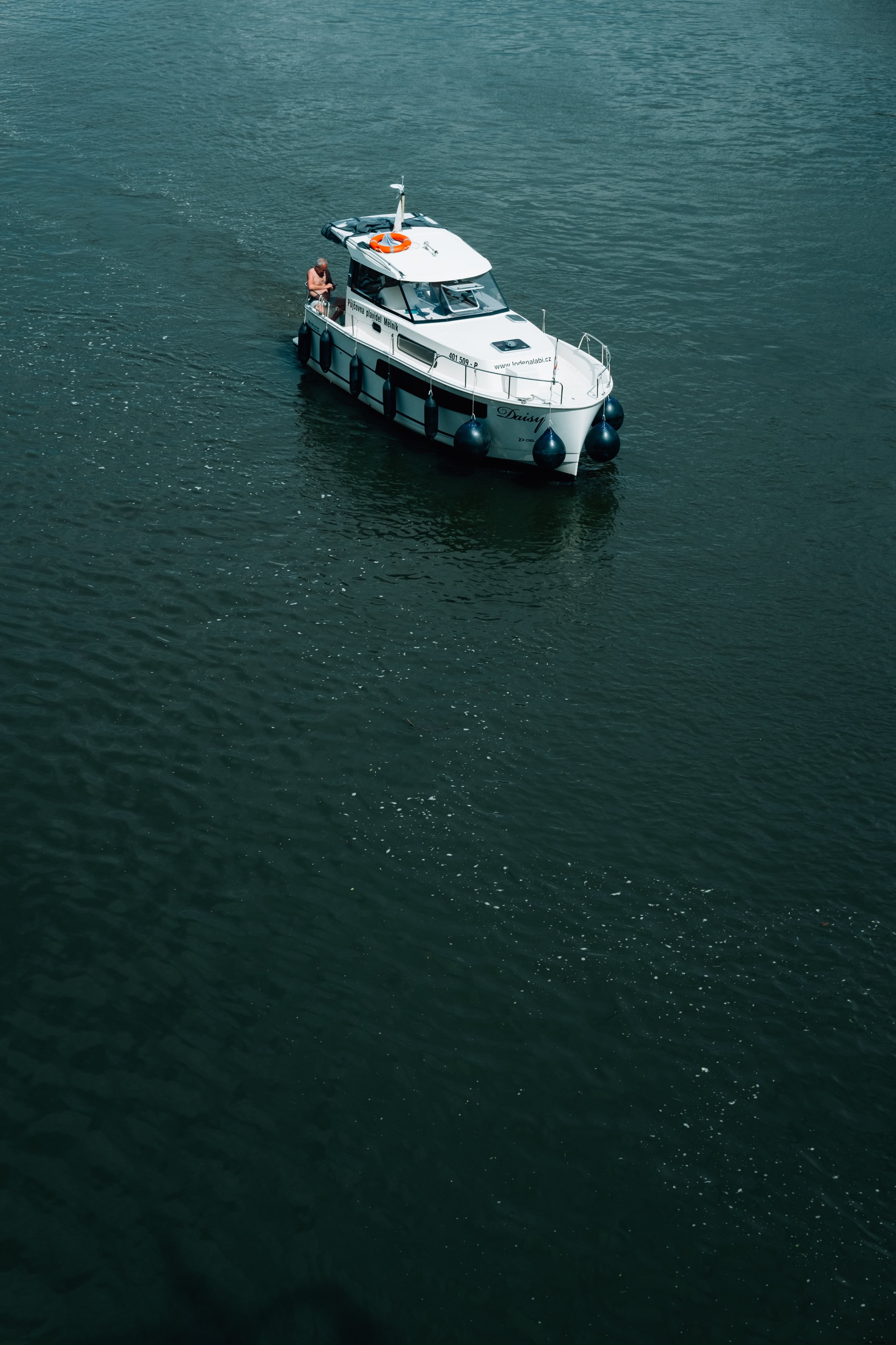 Barco branco com foto de pessoa em água azul escura 
