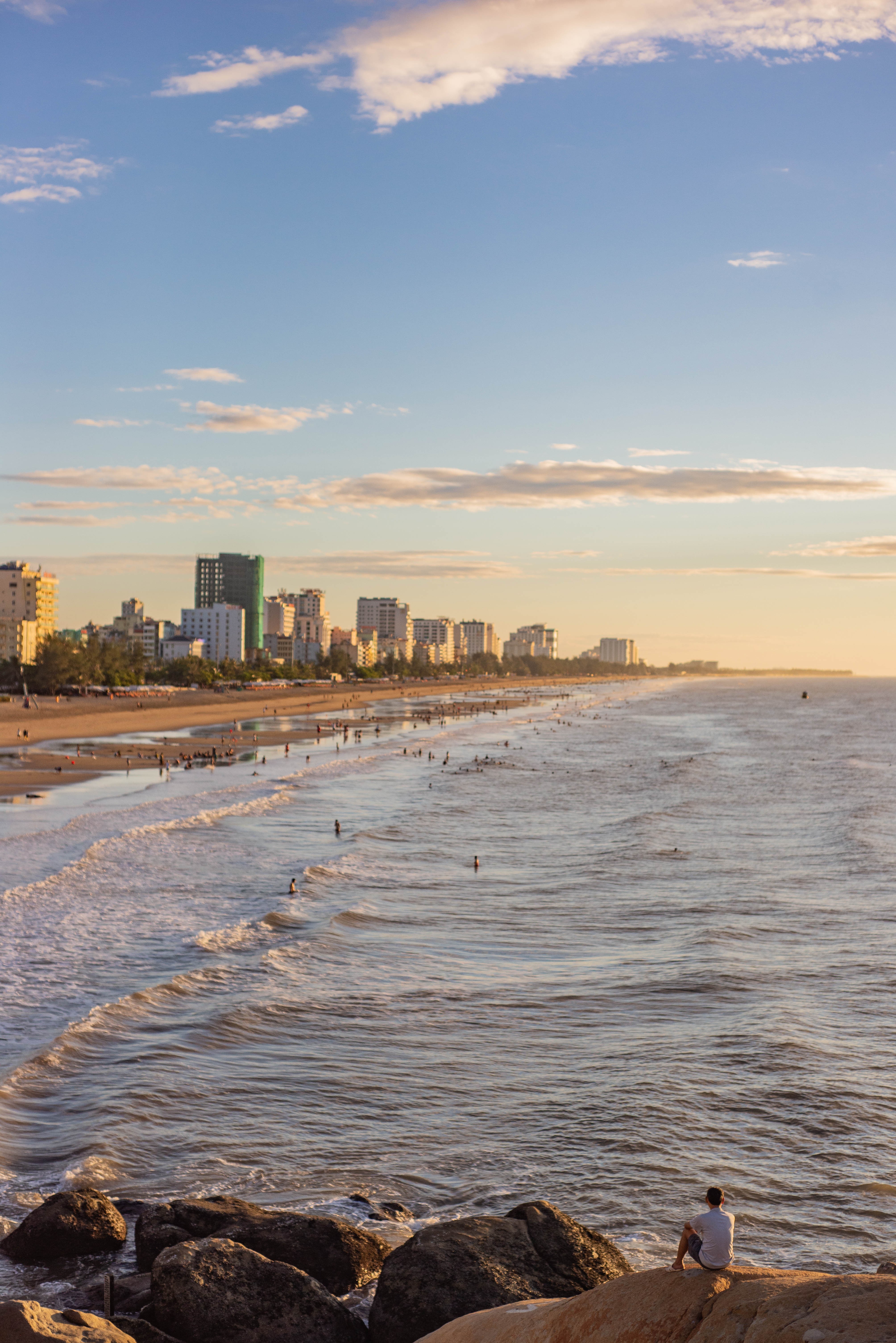 Praia movimentada com edifícios urbanos ao redor da costa. 