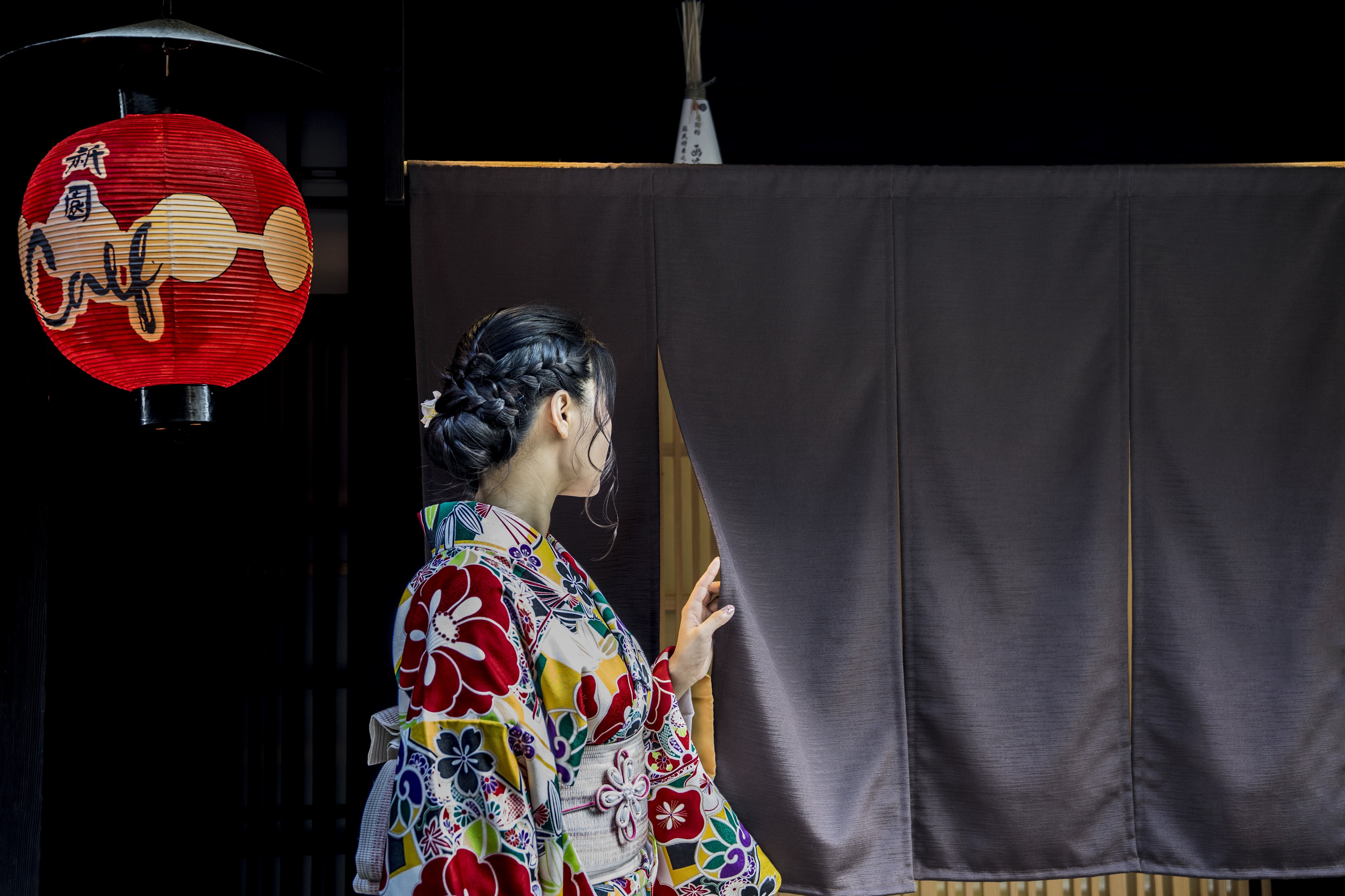 Persona en kimono picos detrás de una foto de cortina negra 