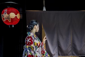 Persona en kimono picos detrás de una foto de cortina negra 
