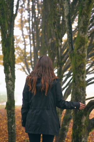 Foto de uma pessoa olhando para árvores cobertas de musgo 