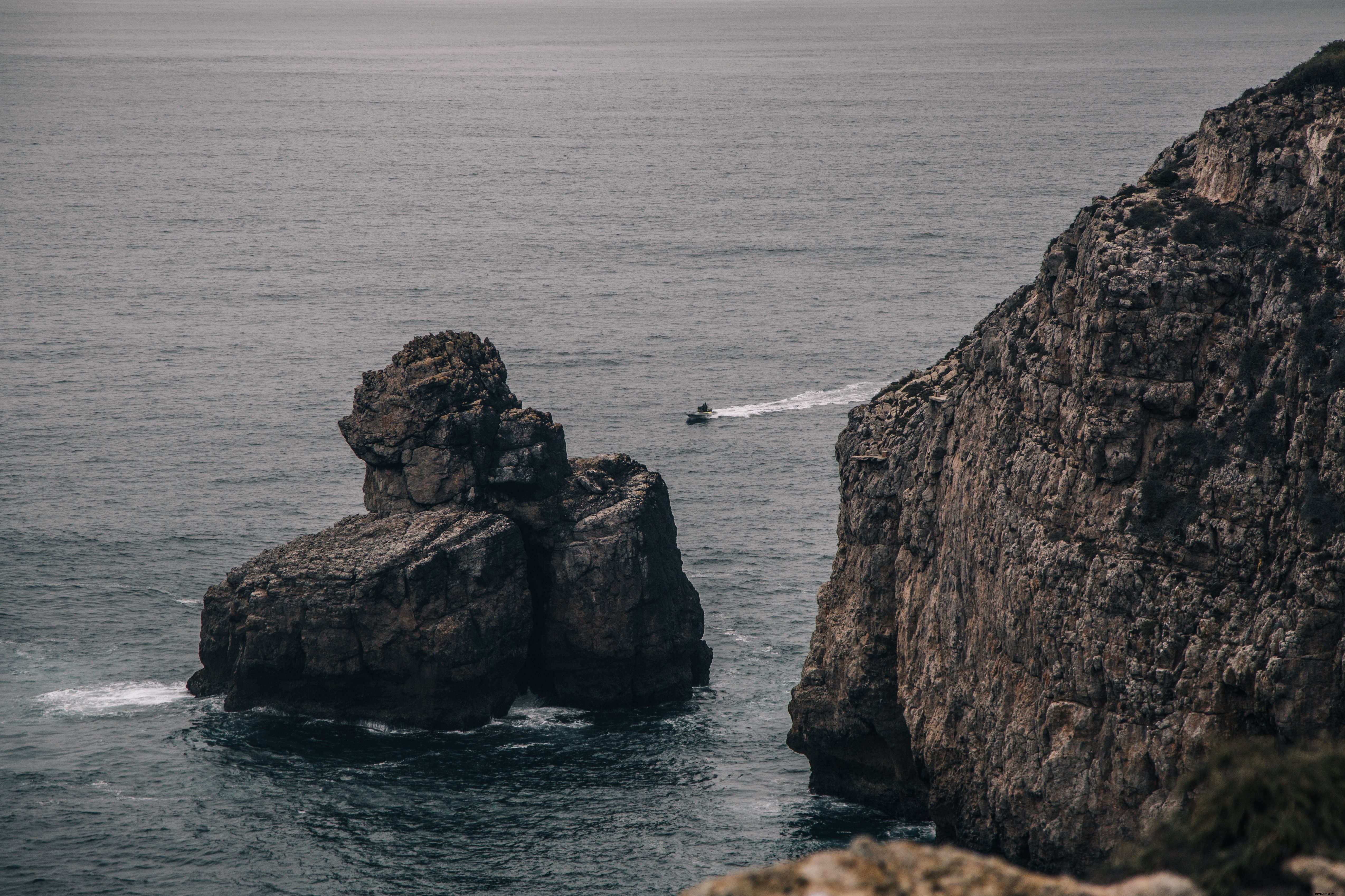 Um bote corta o mar cinzento. Foto 