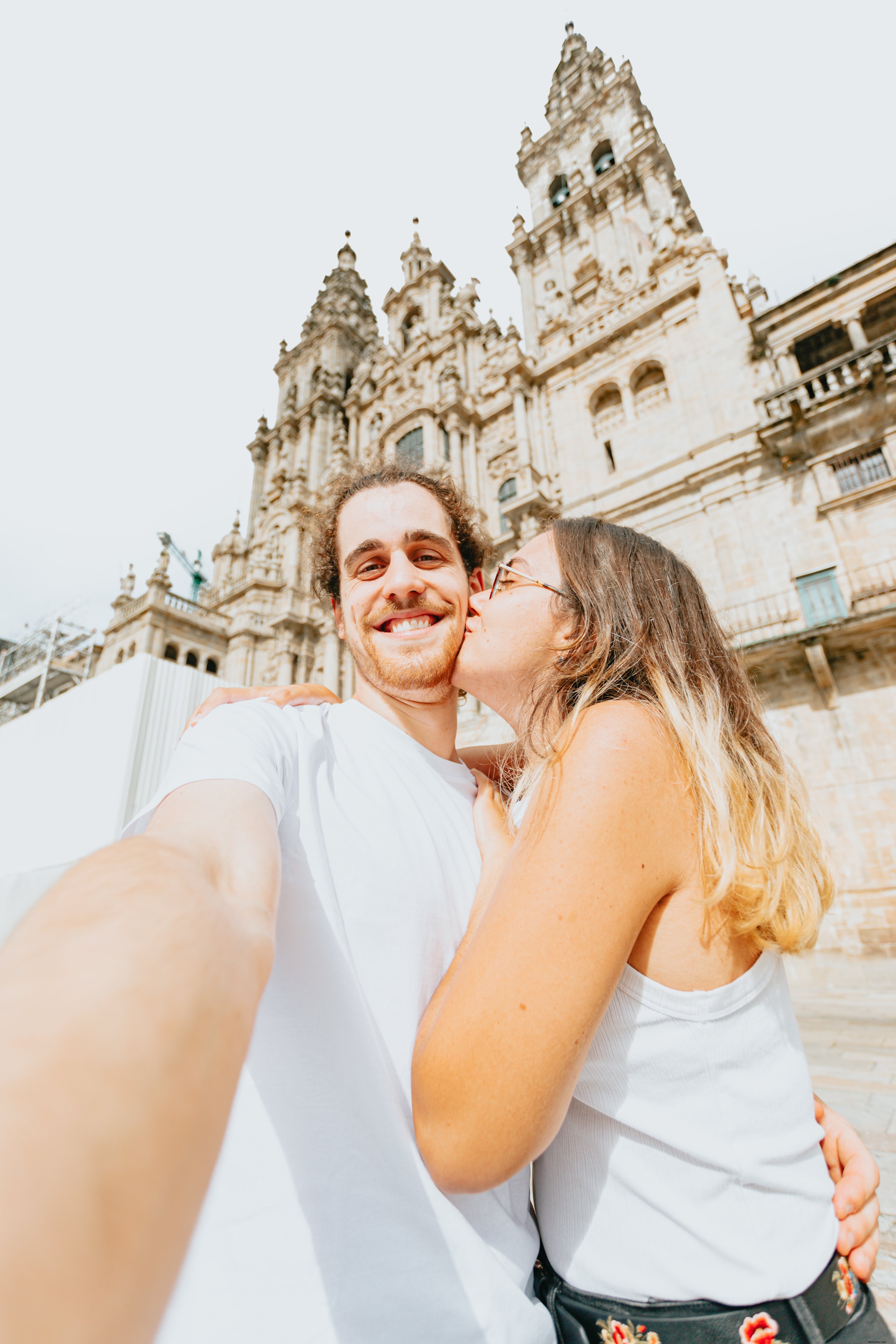 Homem tira uma selfie enquanto uma mulher o beija. Foto 